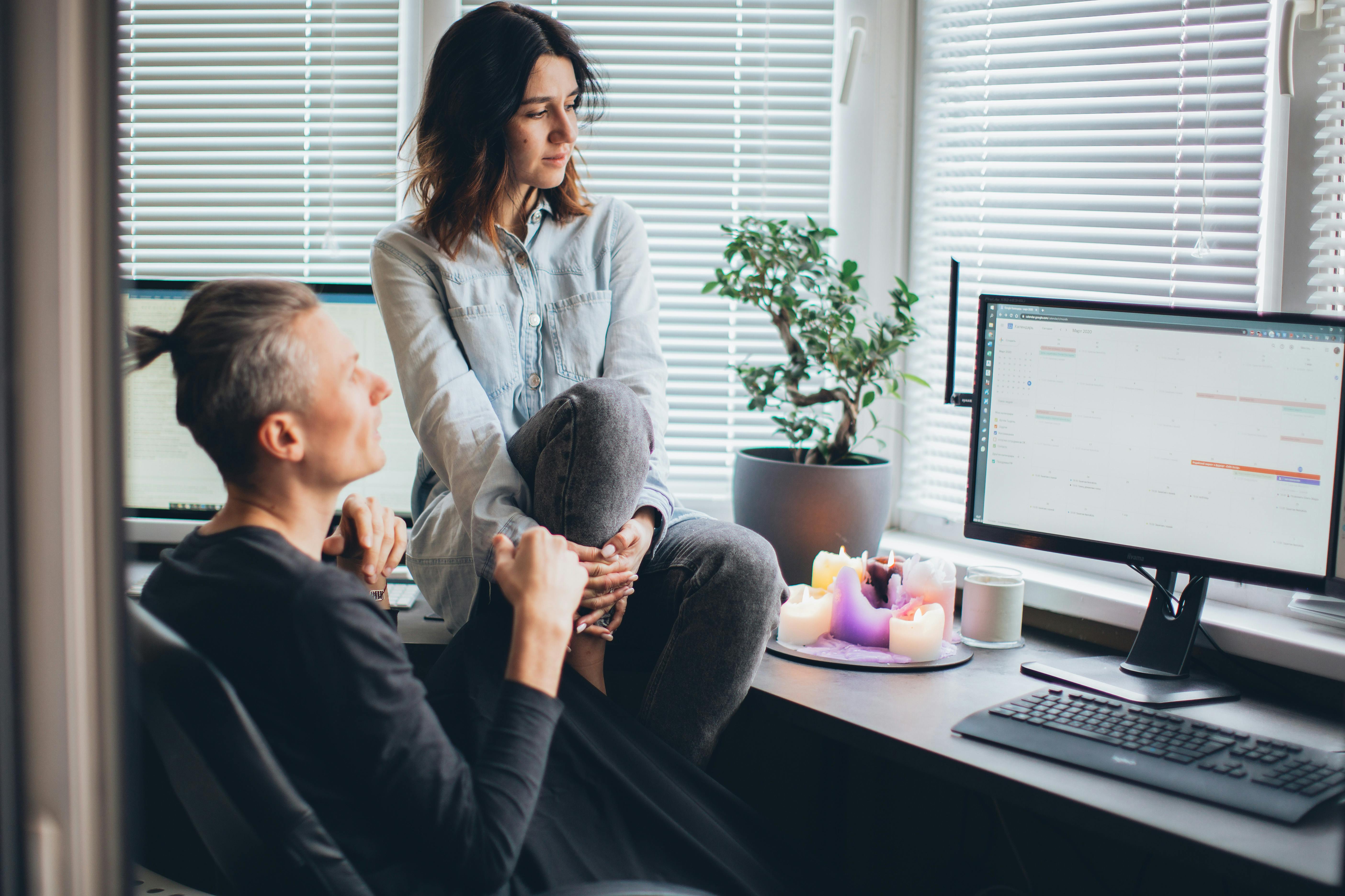 Man with a woman sitting on a desk | Source: Pexels
