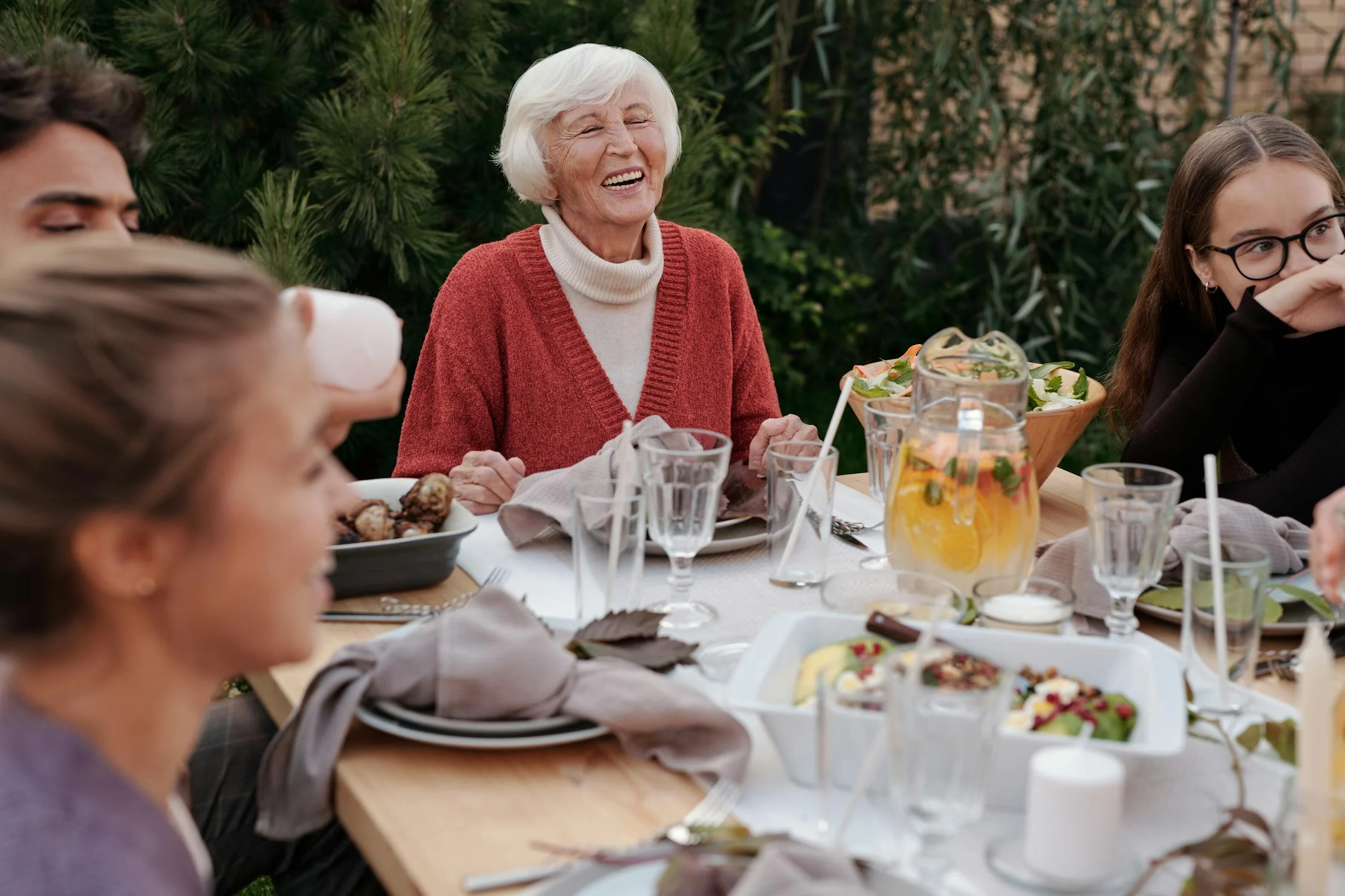 An elderly woman laughing at a family gathering | Source: Pexels