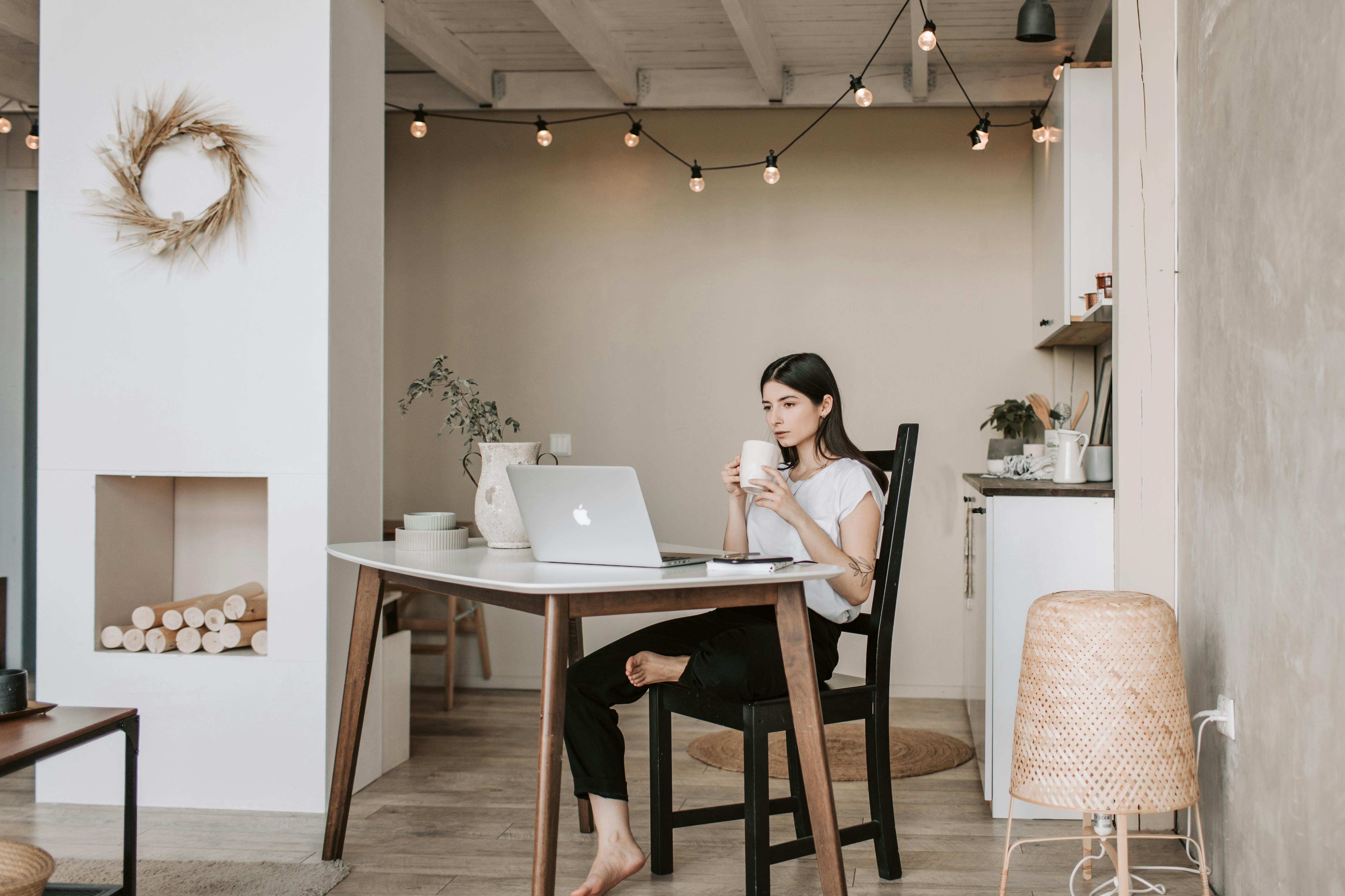 Una mujer bebiendo mientras mira algo en su computadora portátil | Fuente: Pexels