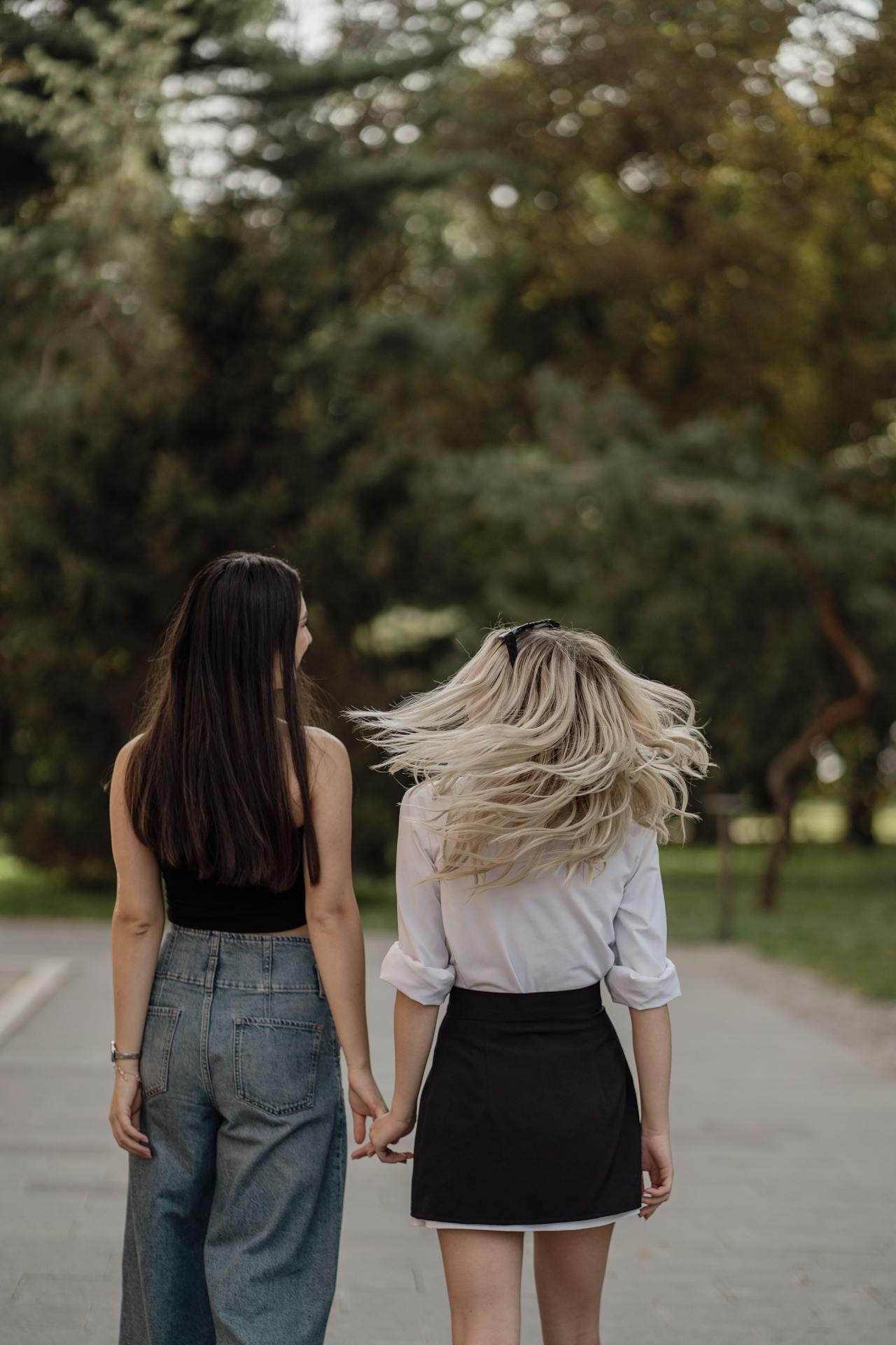 Two women holding hands while walking | Source: Pexels