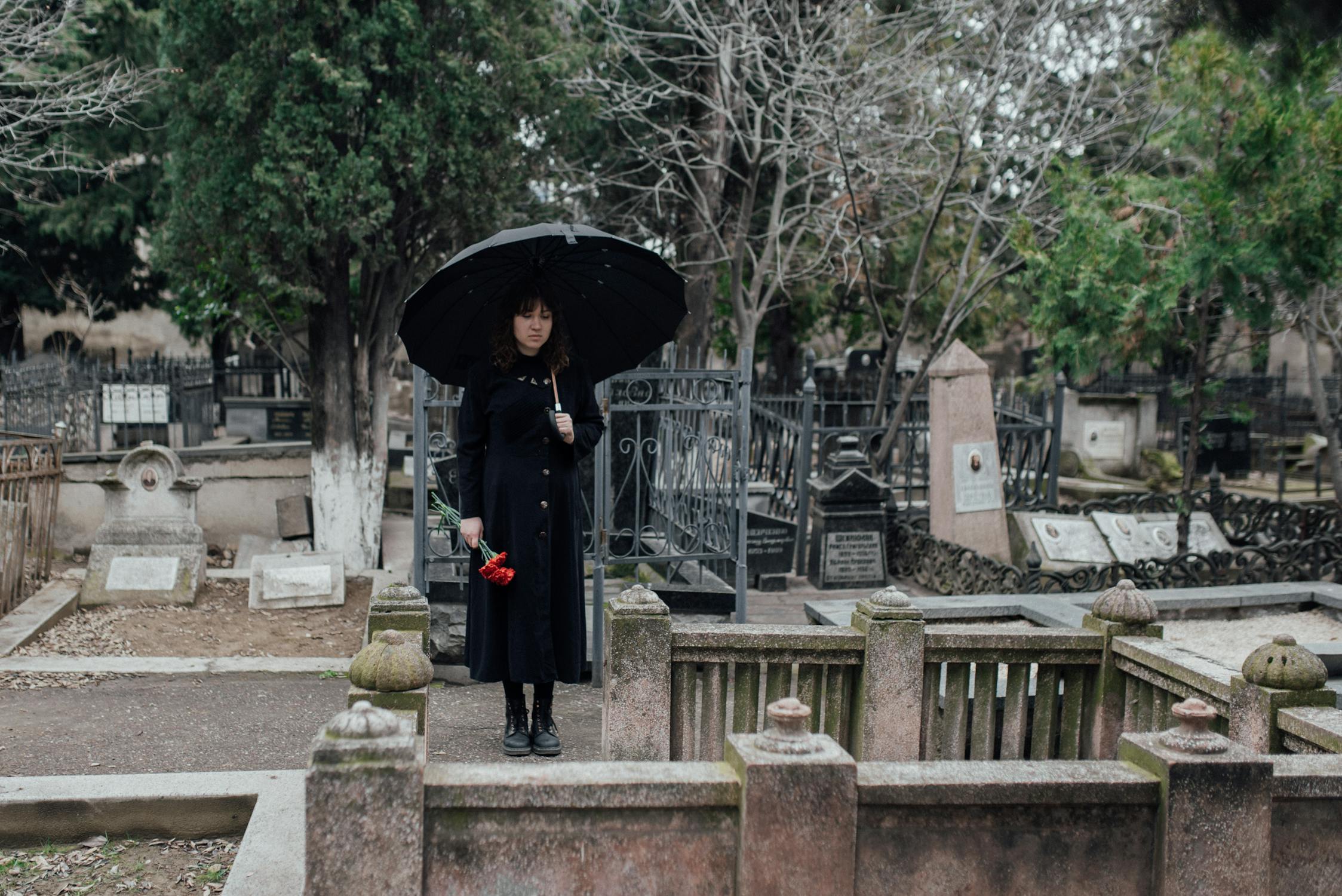 A young woman standing at the cemetery ⏐ Source: Pexels