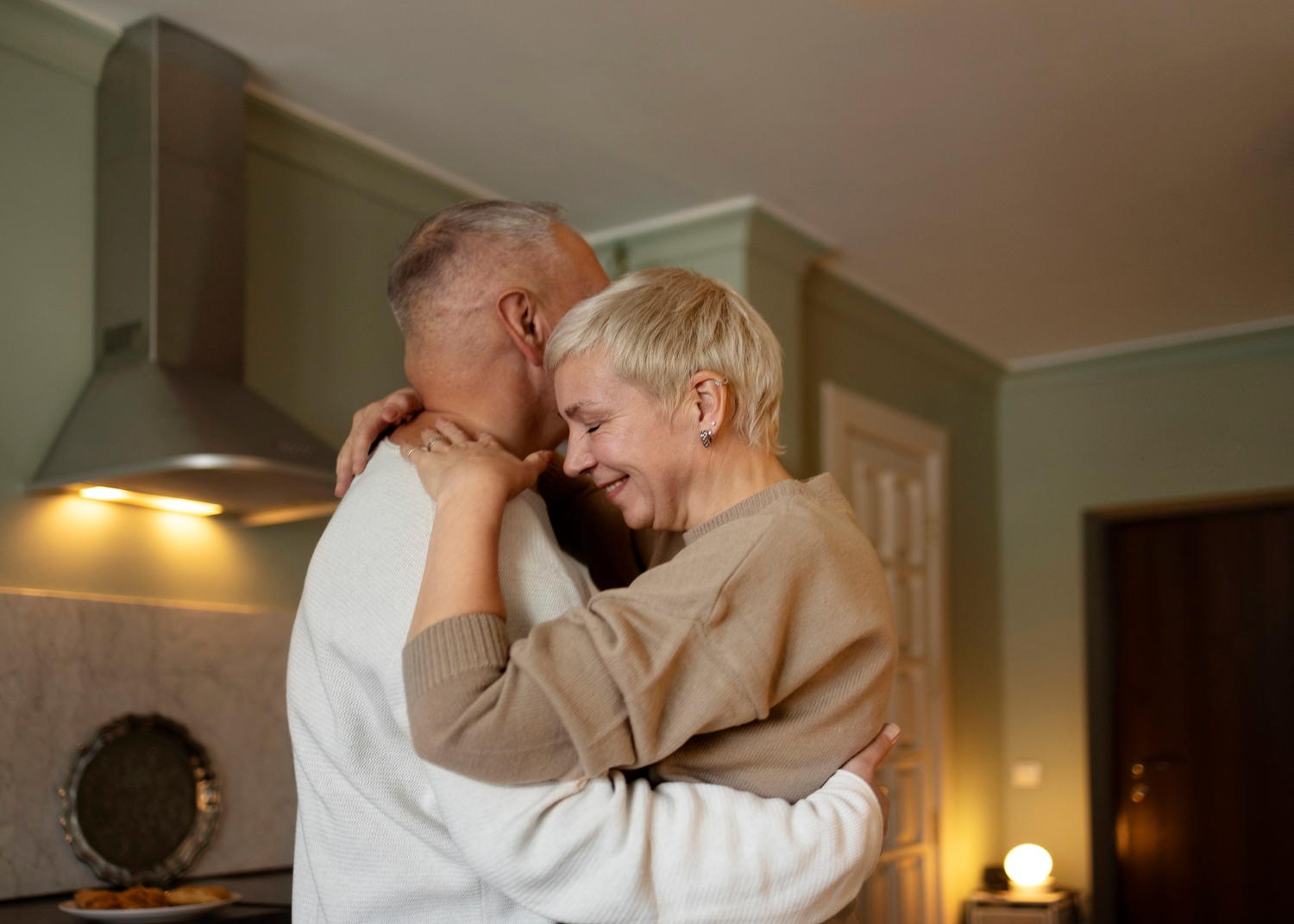 A senior couple embracing each other in the kitchen | Source: Freepik