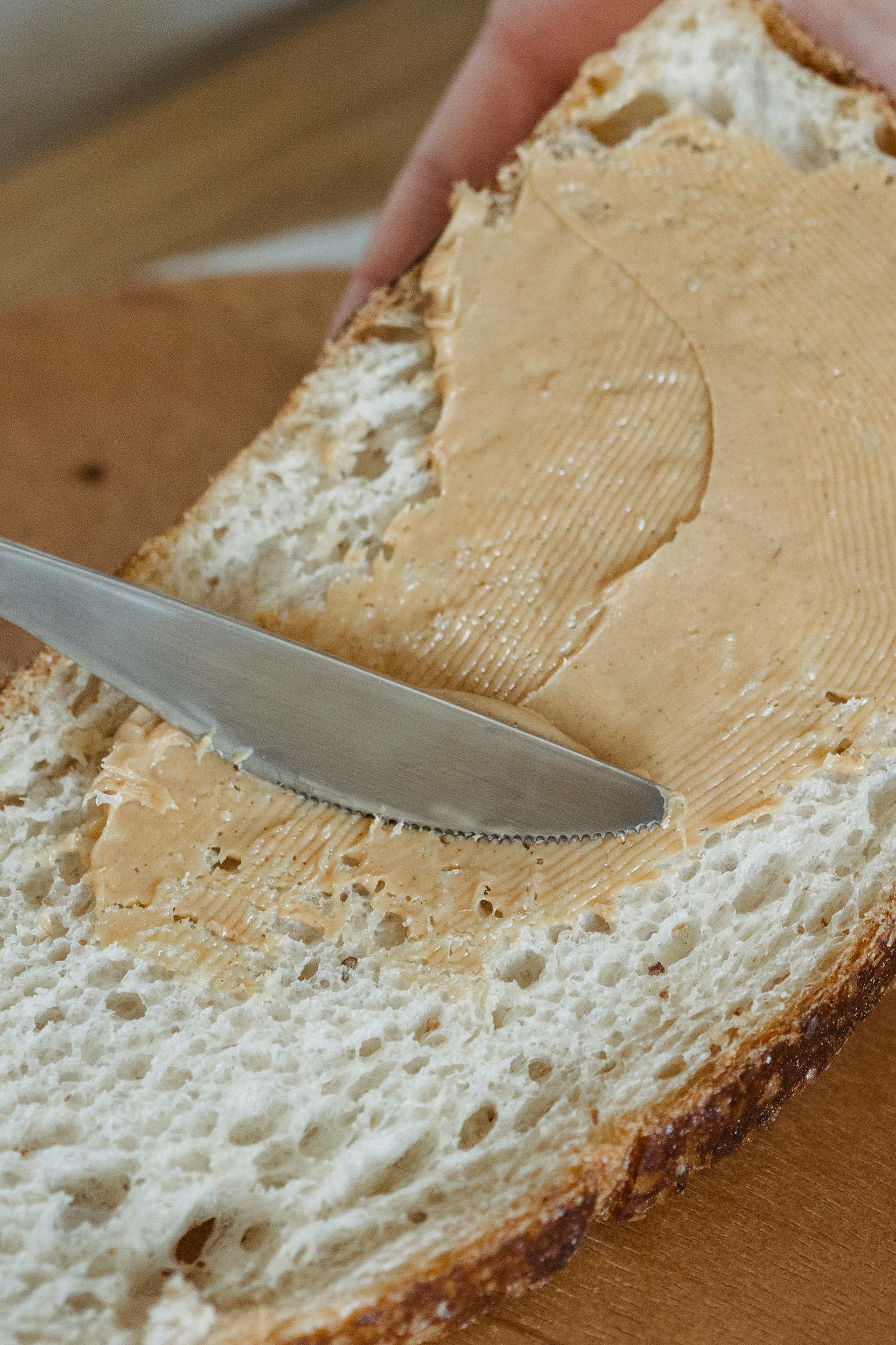 A person putting peanut butter on a slice of bread | Source: Pexels