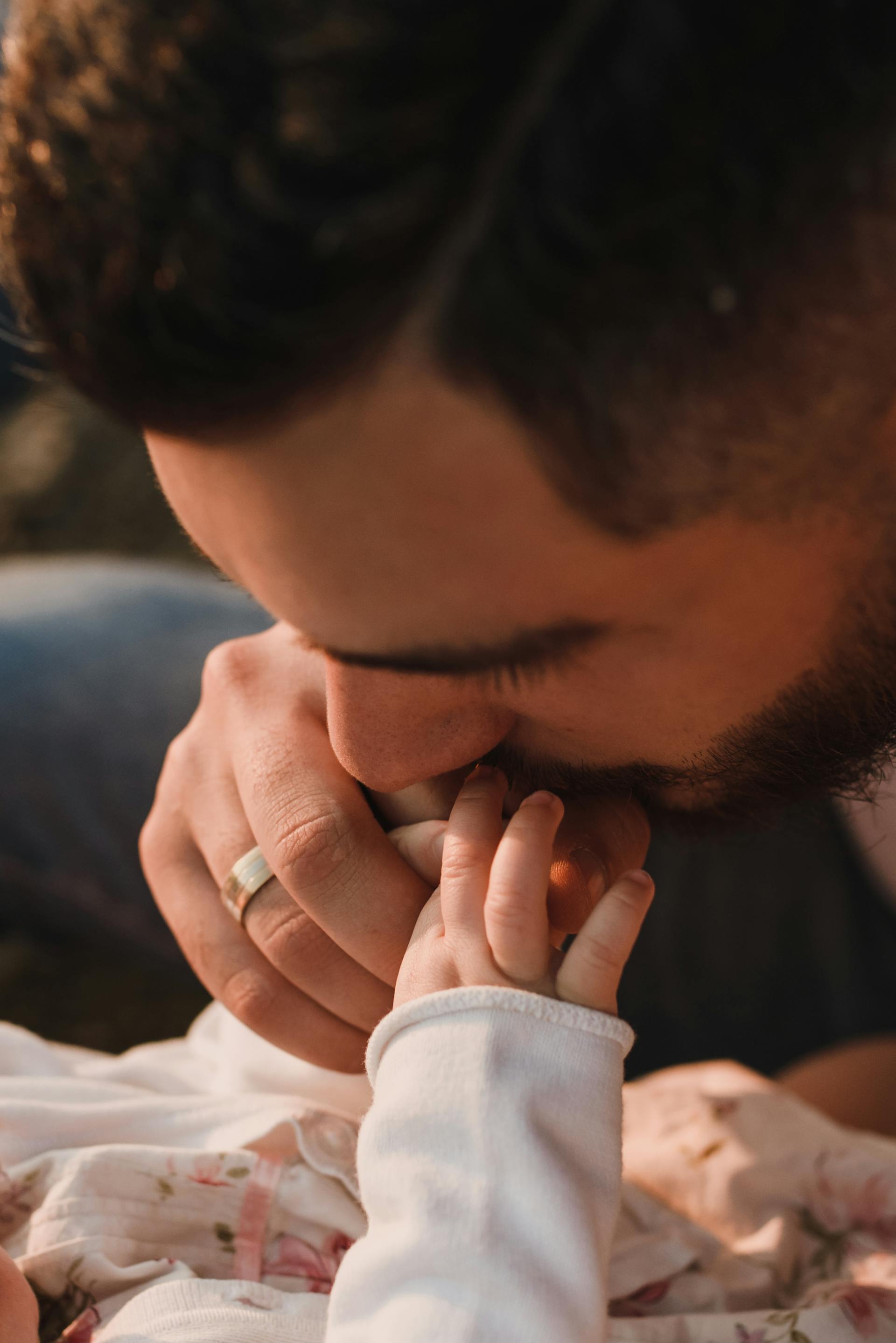 A close-up shot of a father kissing his baby's hand | Source: Pexels