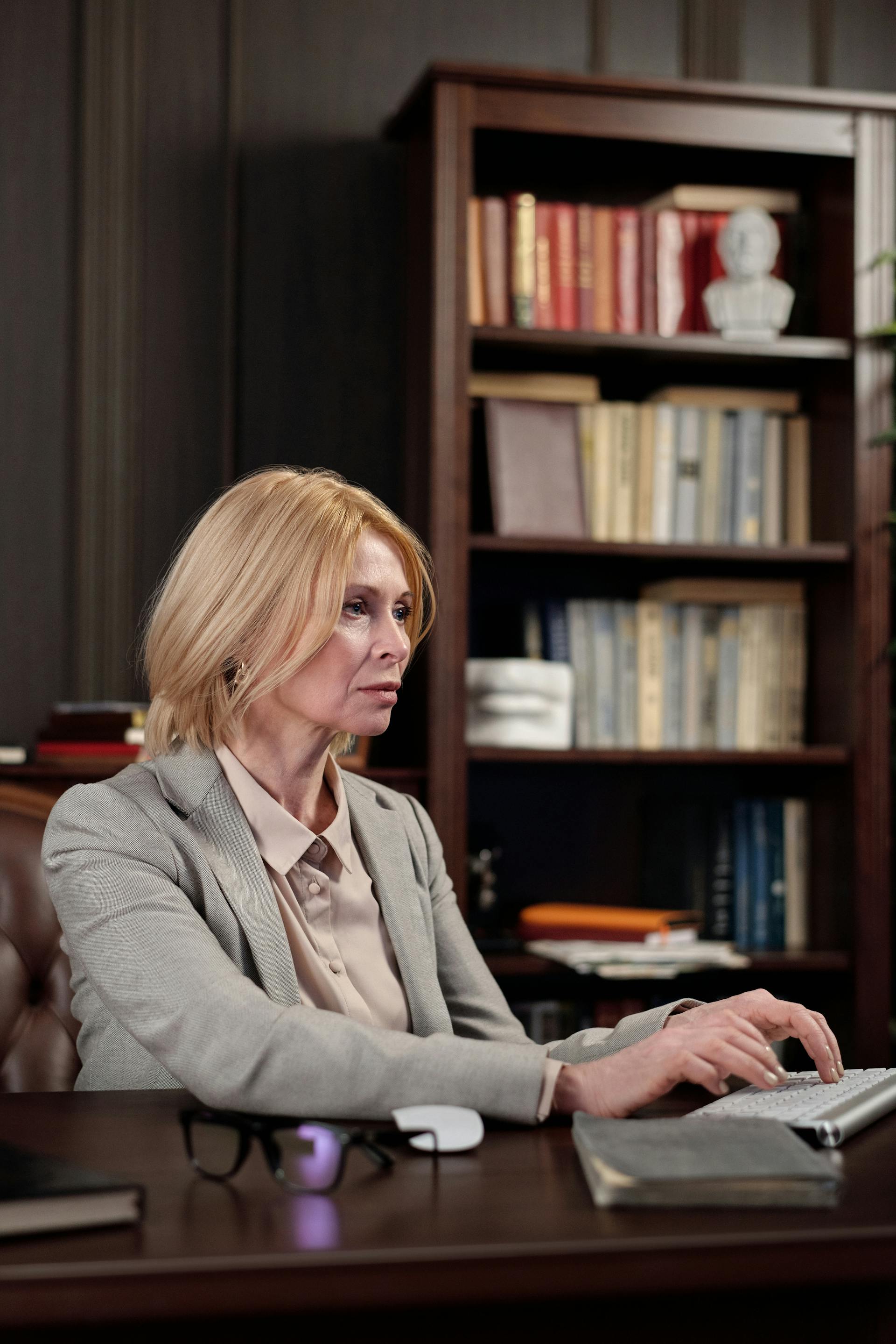 A mature woman with blond hair sitting at her desk and working on her computer | Source: Pexels
