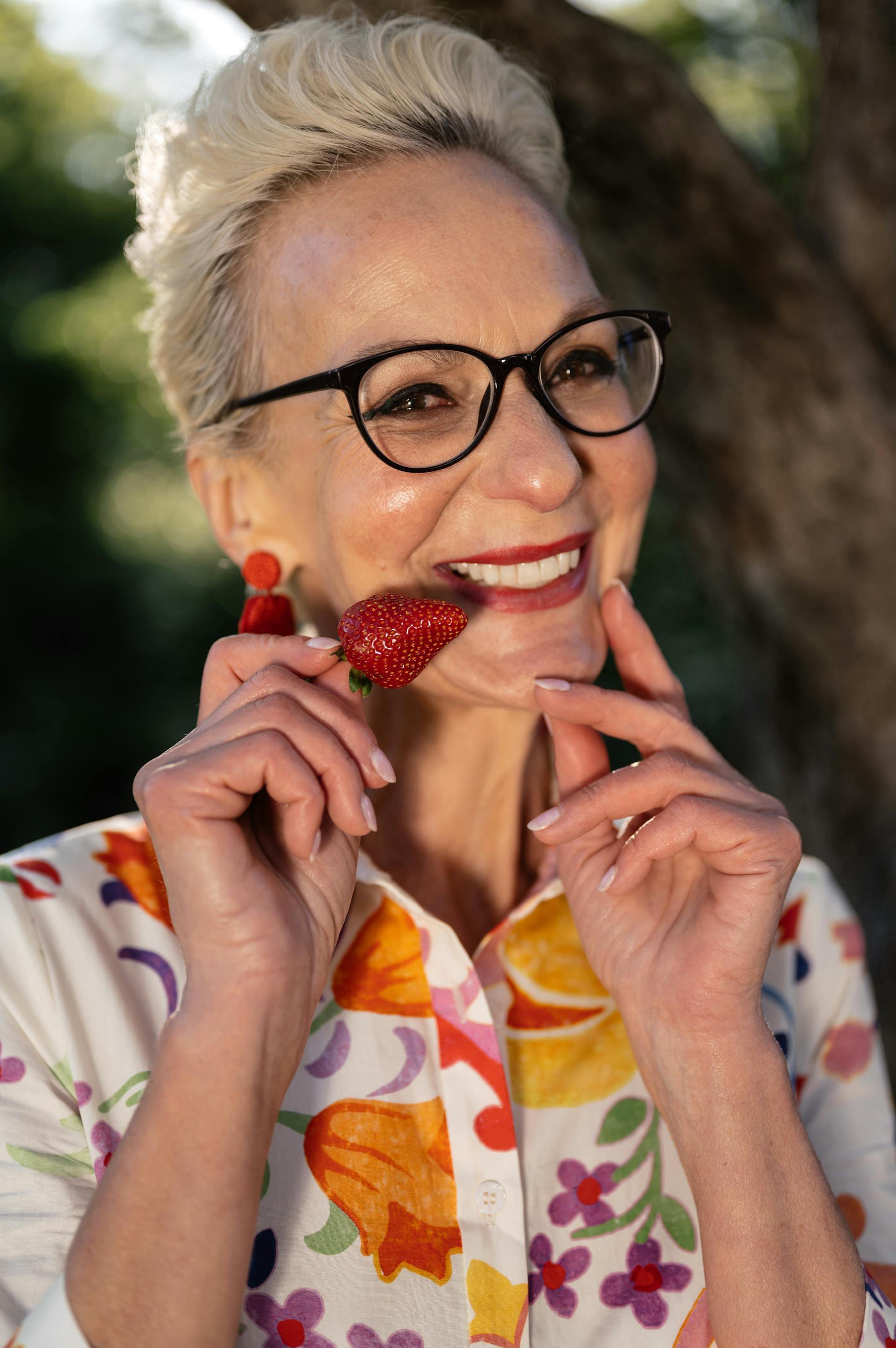 A senior woman holding a strawberry | Source: Pexels
