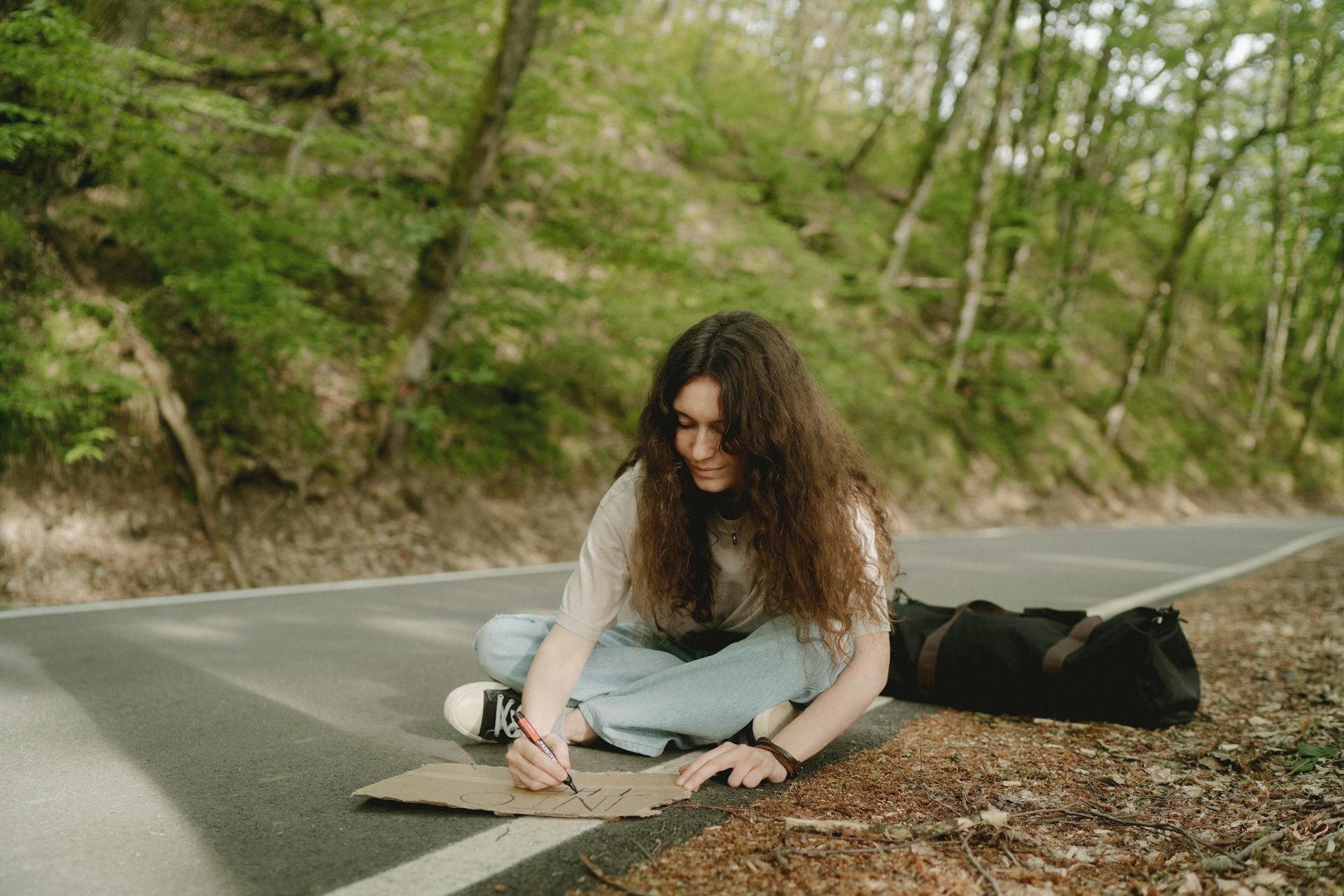 A woman writing on a piece of cardboard | Source: Pexels