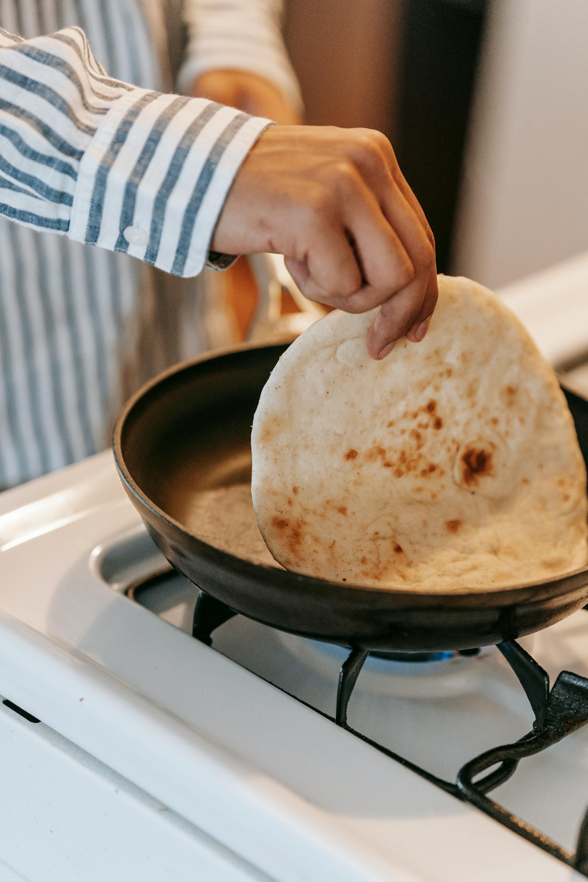 Un homme prépare du pain plat cuit à la poêle dans la cuisine | Source : Pexels