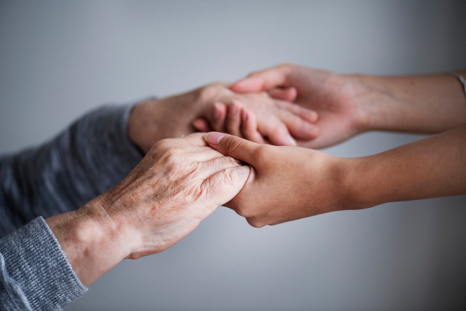 Close-up shot of a young woman holding an older lady's hands | Source: Freepik