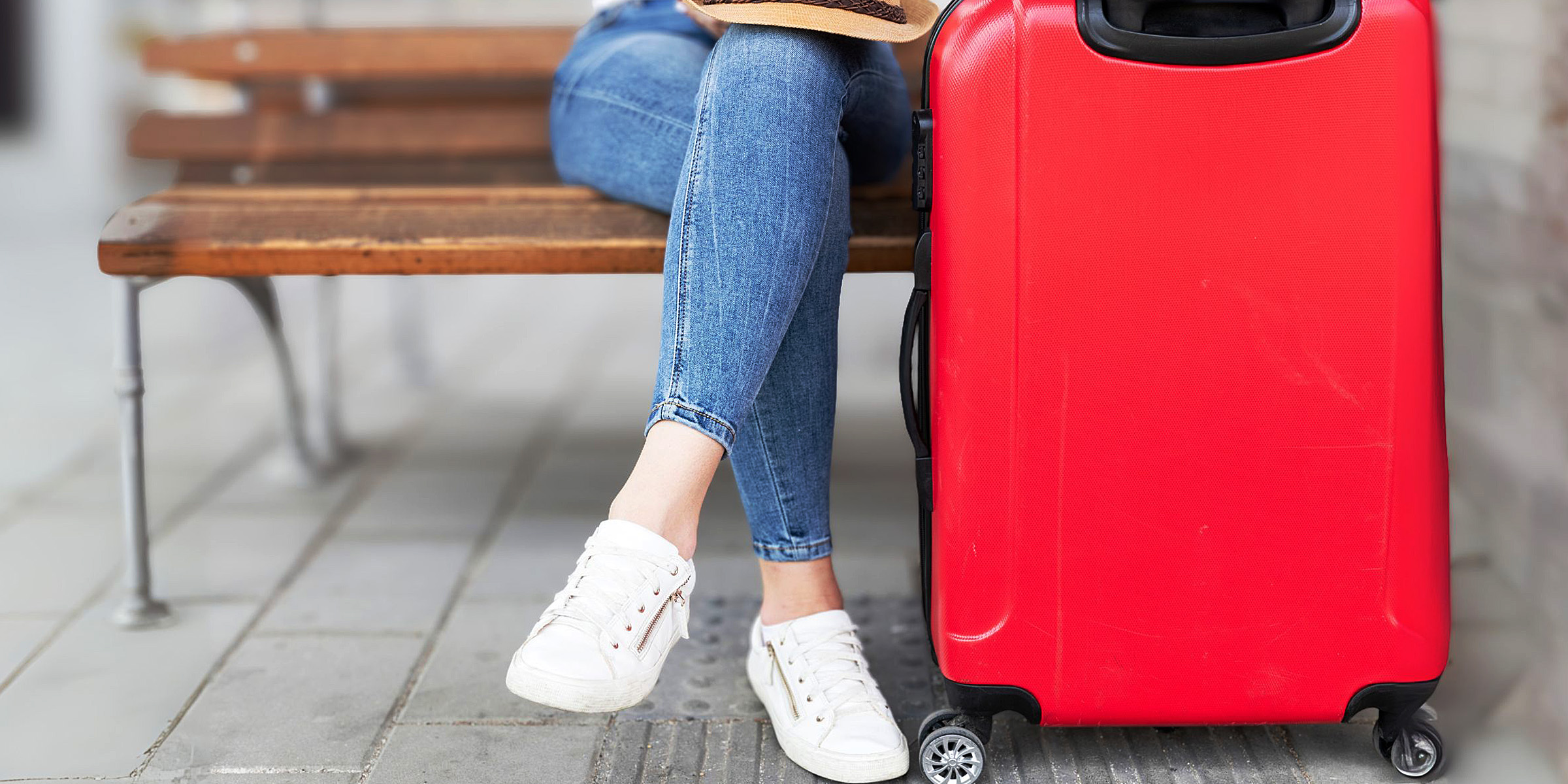 A person seated next to a red suitcase | Source: Freepik