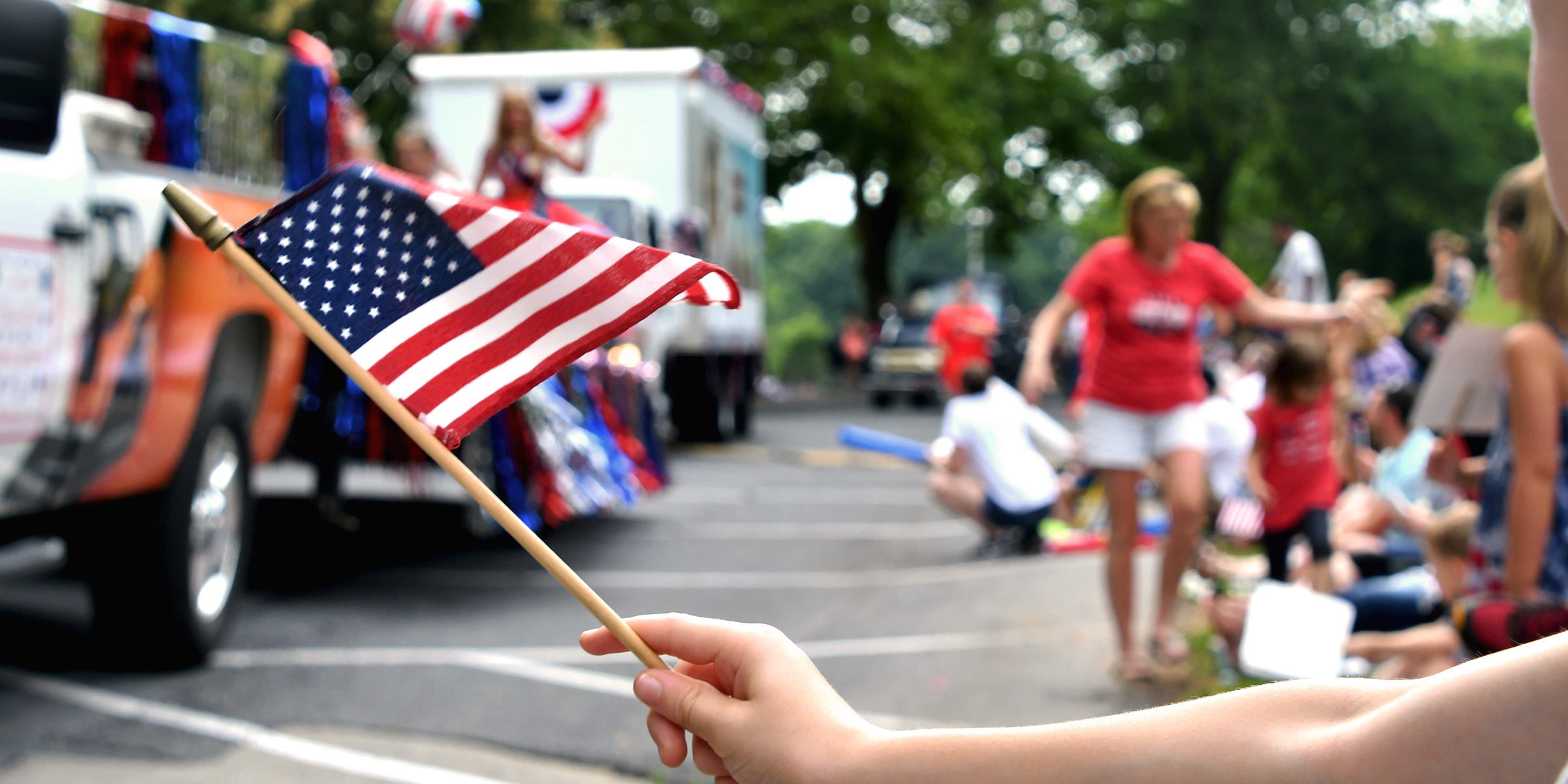 A person waving an American flag during a lively 4th of July parade | Source: Shutterstock