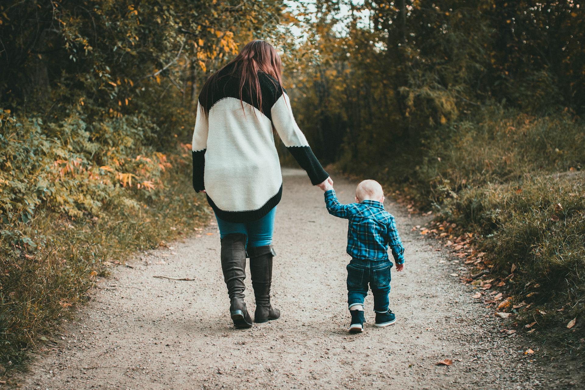 A woman holding her little son's hand as they walk together | Source: Pexels