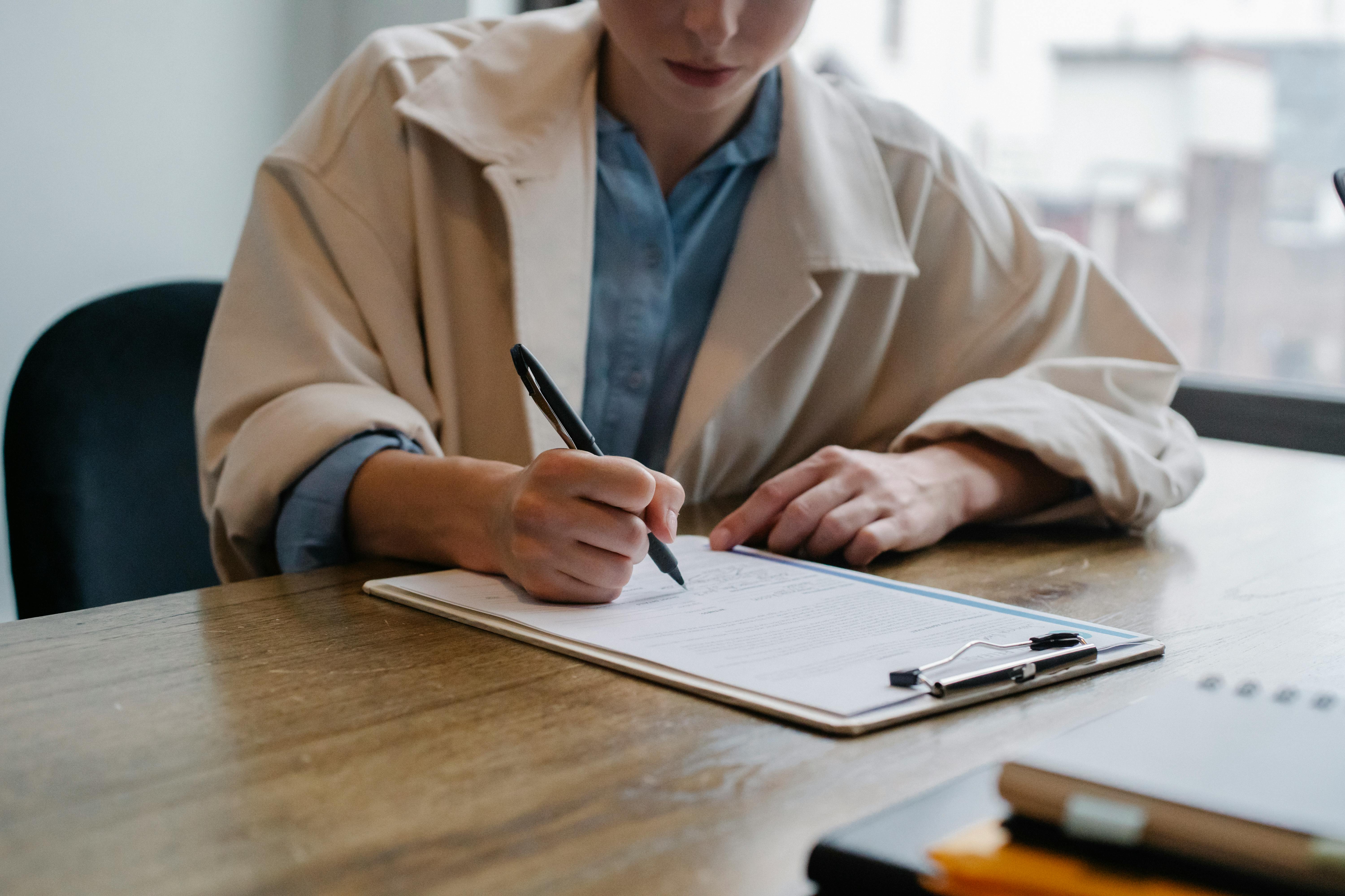 A woman filling out paperwork | Source: Pexels