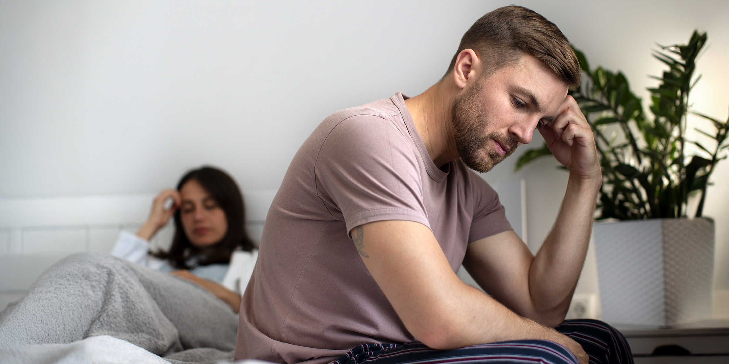 An upset couple sitting on a bed | Source: Freepik