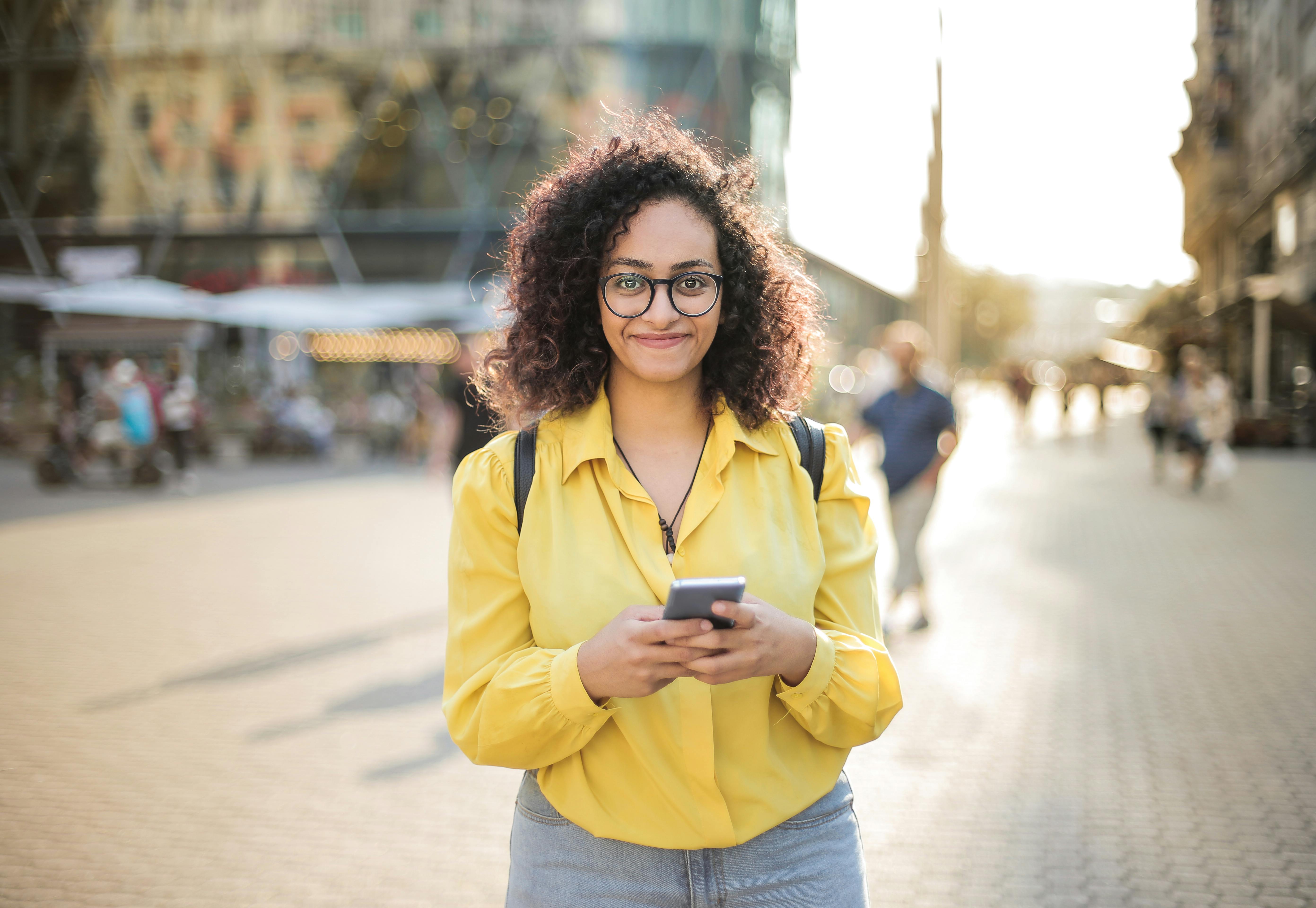 A happy woman holding her phone | Source: Pexels