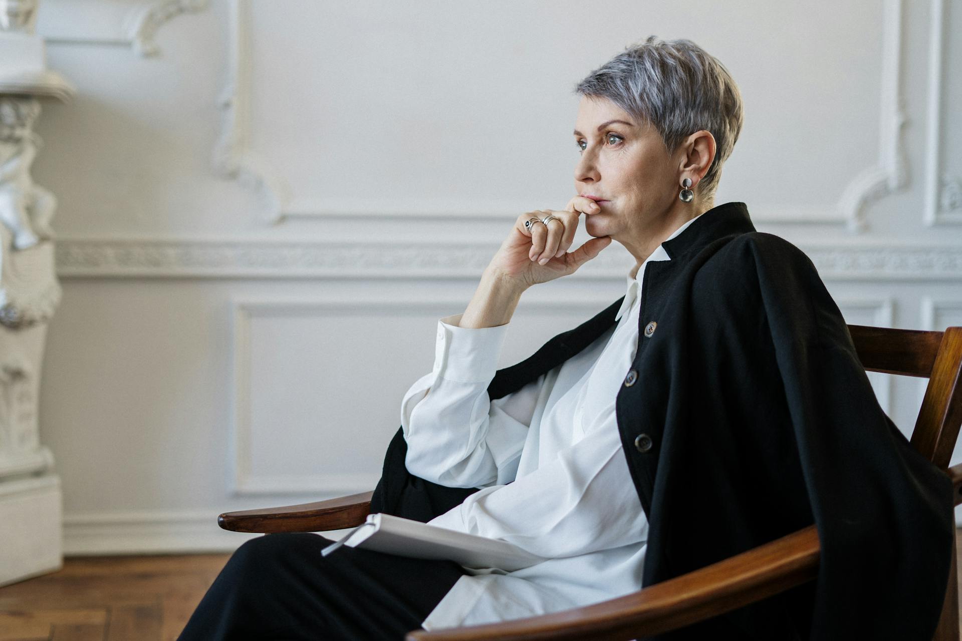 A woman in a white shirt and black blazer is sitting on a chair and listening intently | Source: Pexels