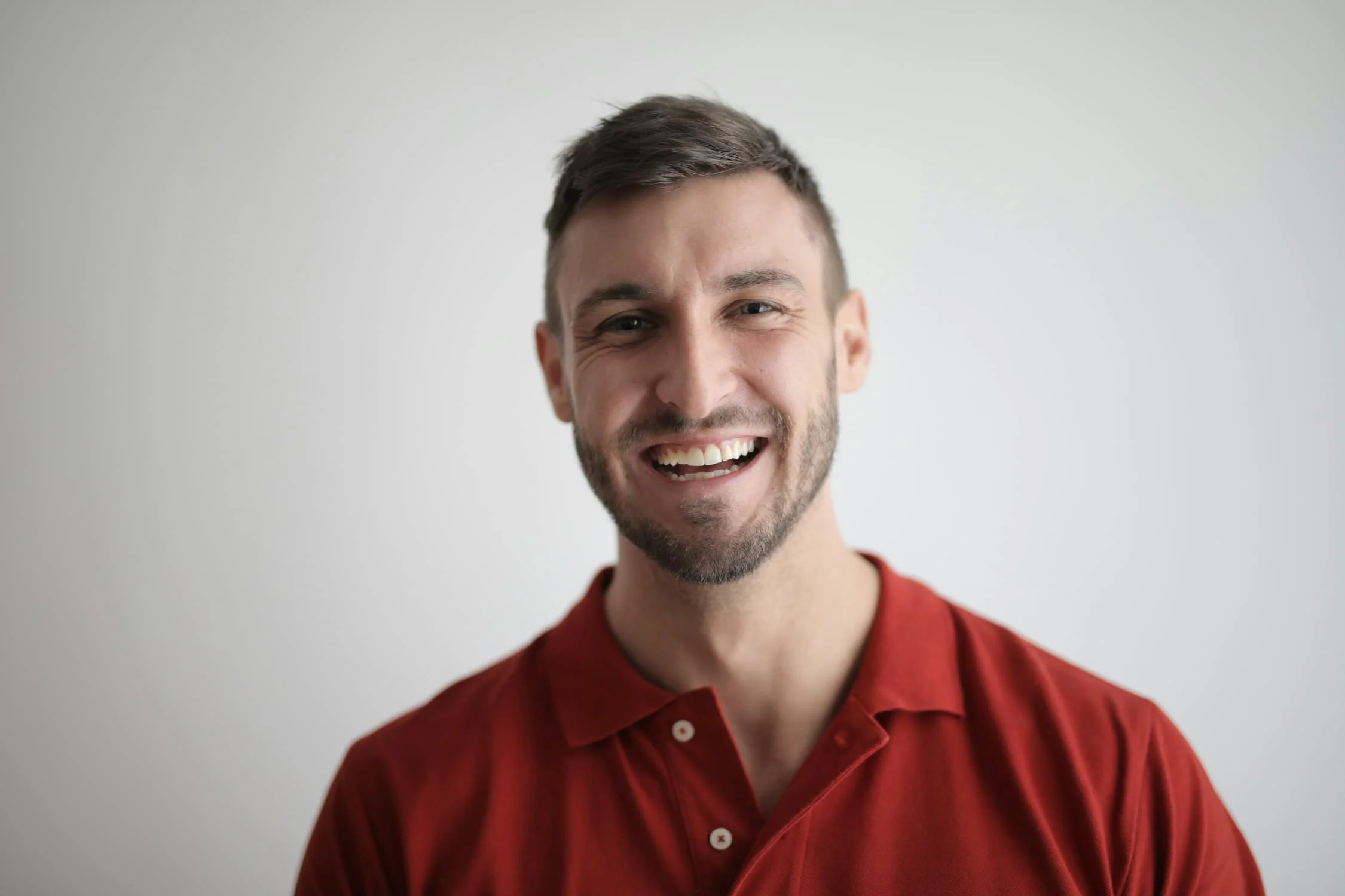 A laughing man wearing a red polo shirt | Source: Pexels