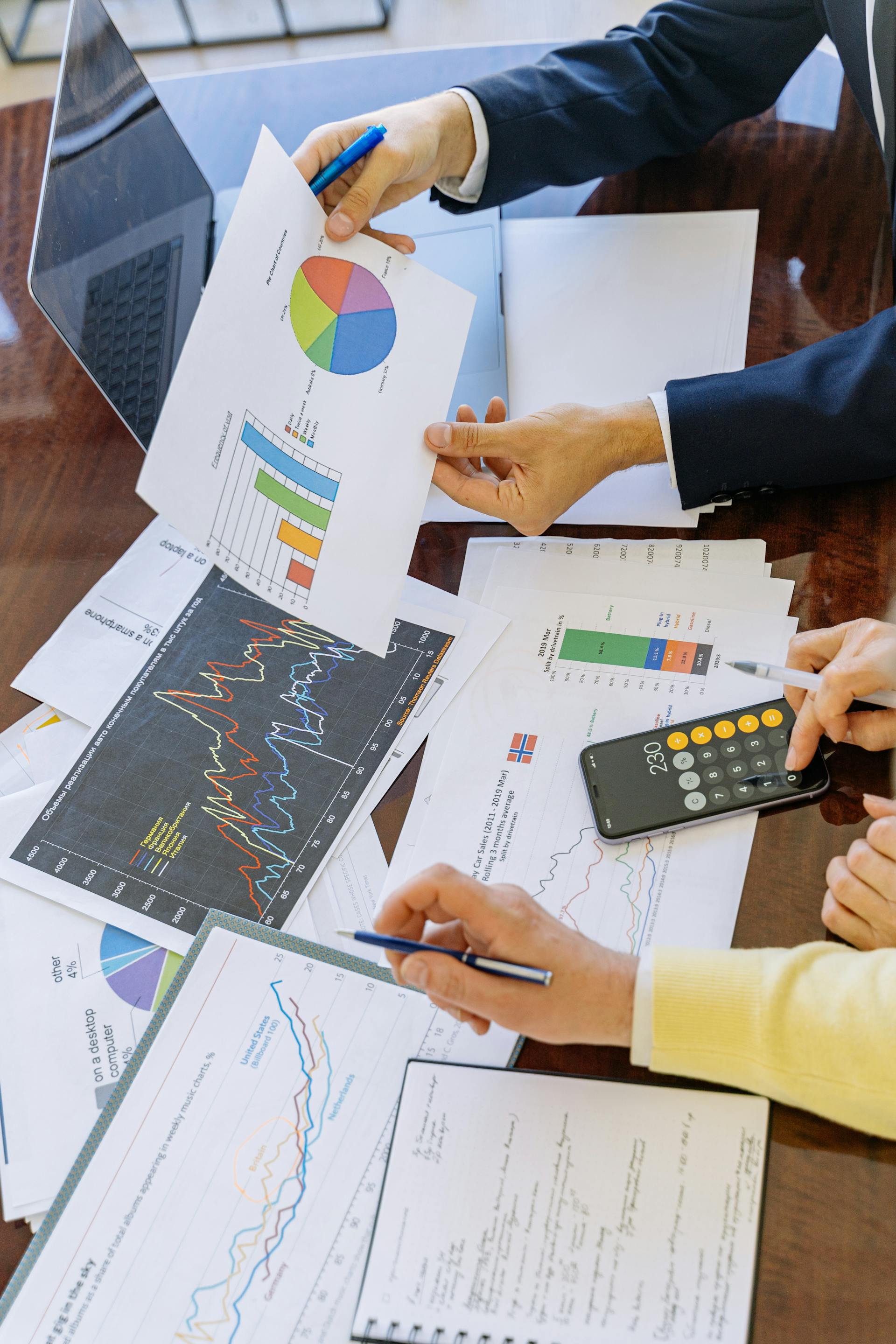 Close-up shot of two people analyzing graphs and pie-charts in an office setting | Source: Pexels