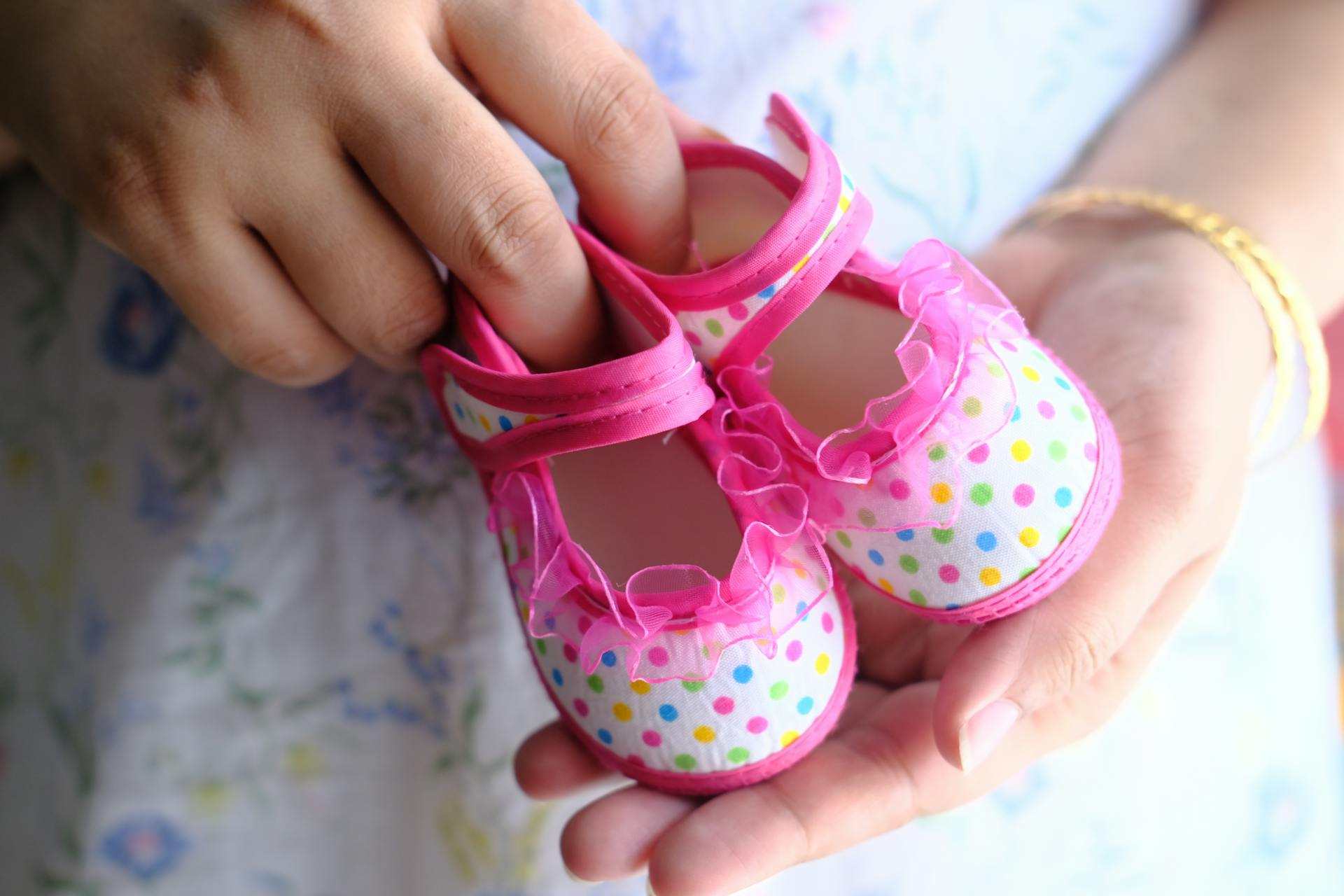A woman holding tiny pink baby shoes | Source: Pexels