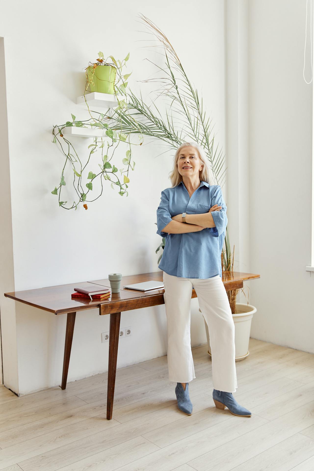 A delighted senior woman standing in a room with her arms crossed | Source: Pexels