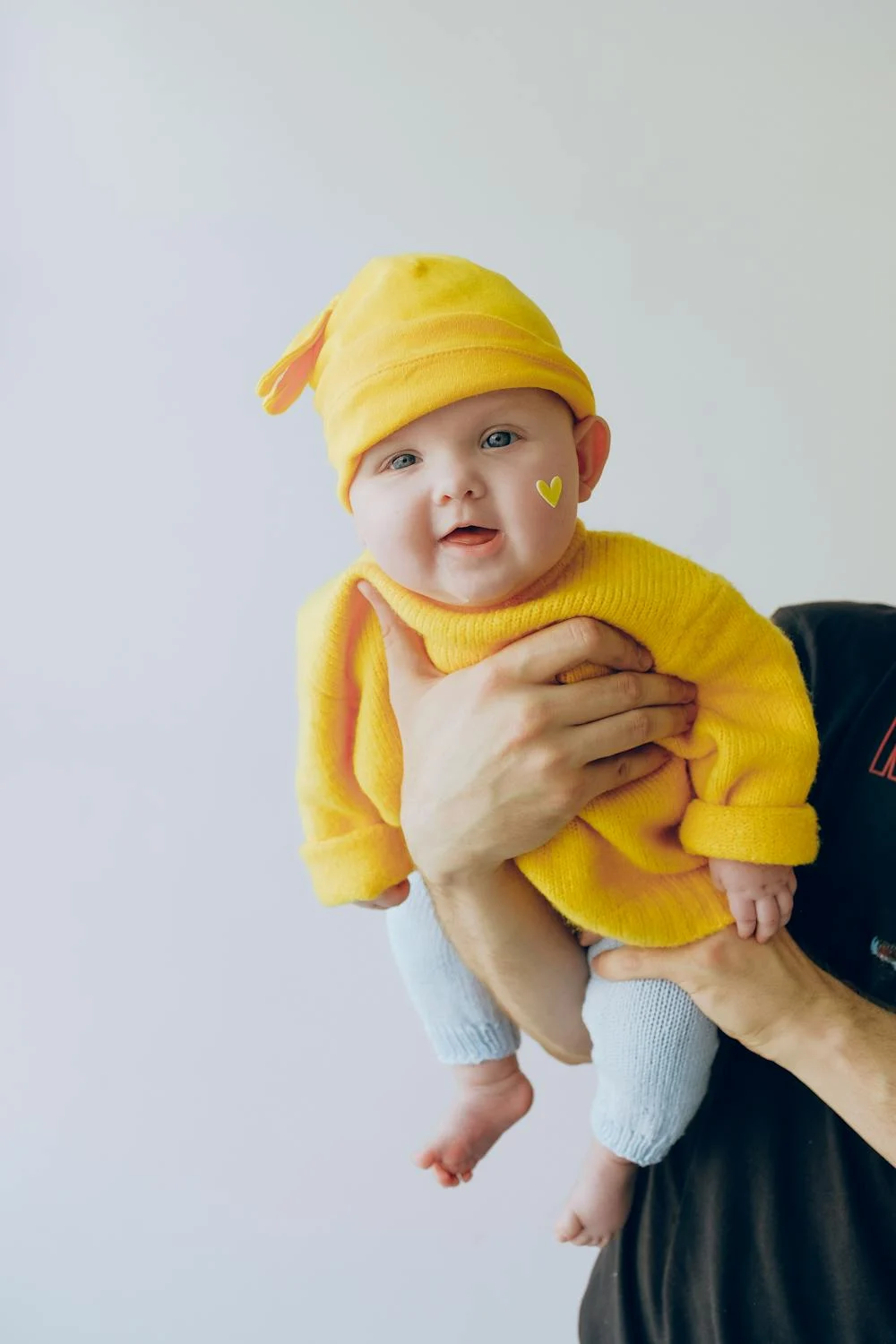 A happy baby in a yellow hat ⏐ Source: Pexels