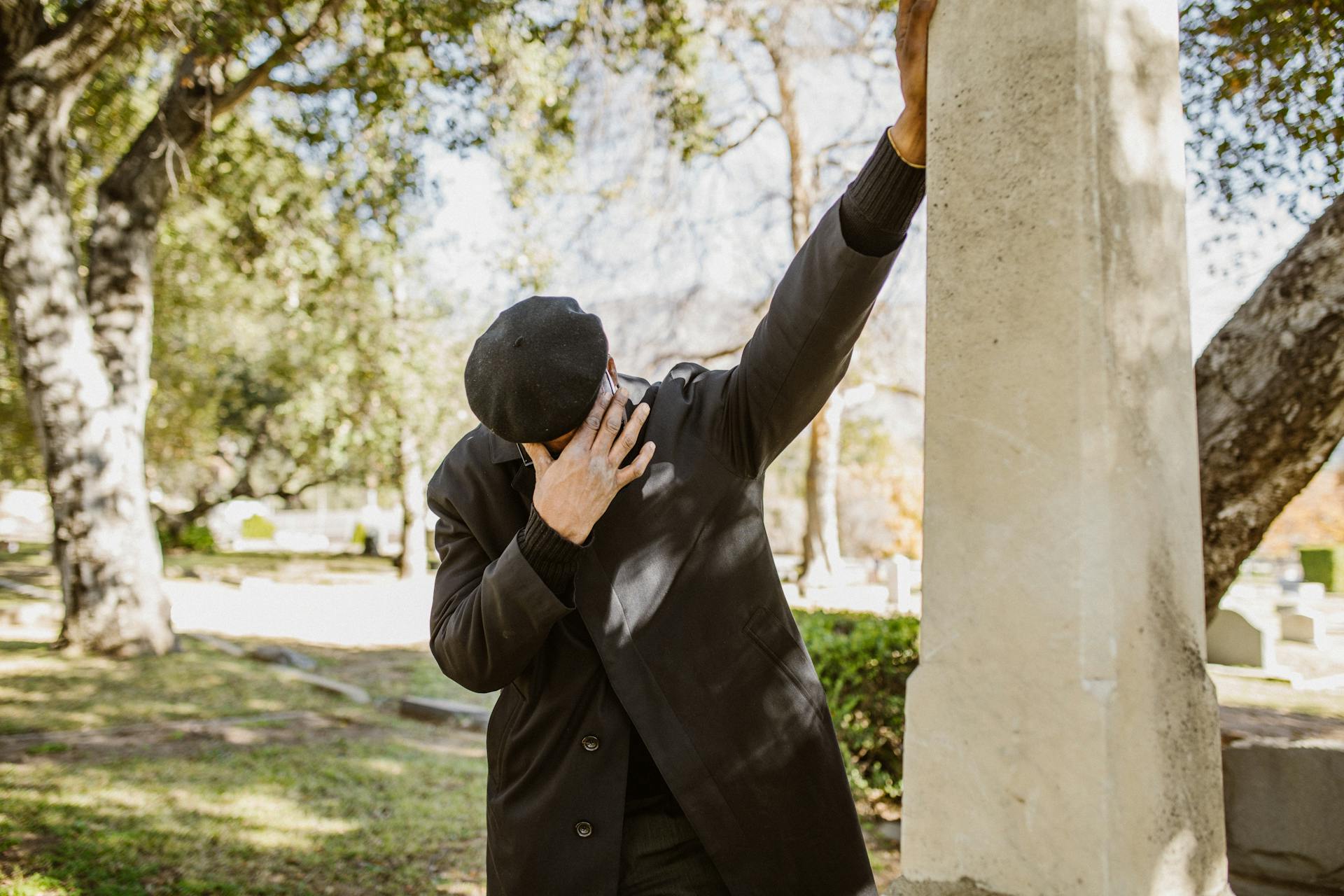 A grieving man standing beside a gray concrete structure | Source: Pexels