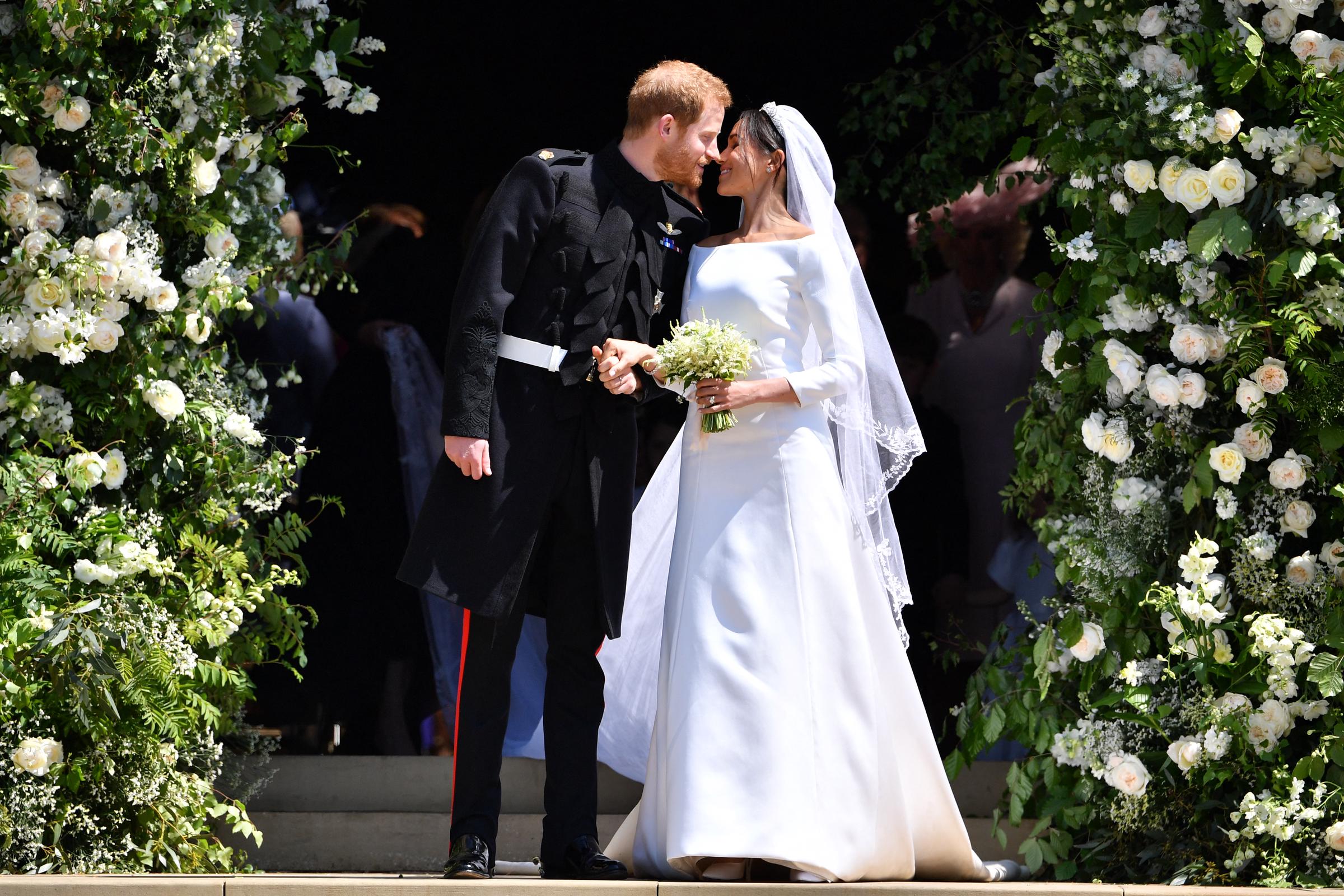 Prince Harry, Duke of Sussex kisses his wife Meghan, Duchess of Sussex as they leave from the West Door of St George's Chapel, Windsor Castle, in Windsor, on May 19, 2018. | Source: Getty Images