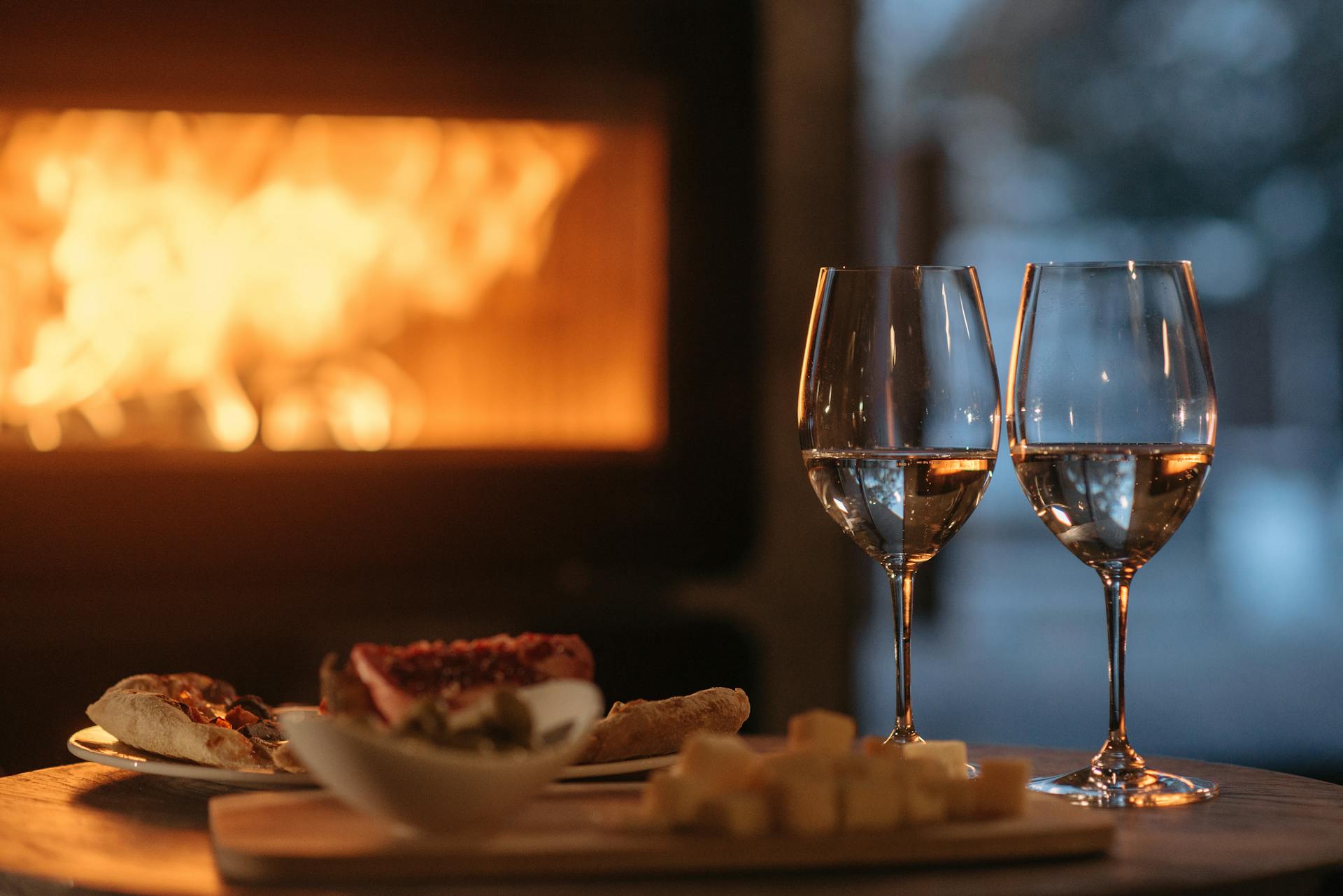 A photo showing two wine glasses lying beside a plate of food on a cozy winter evening | Source: Pexels
