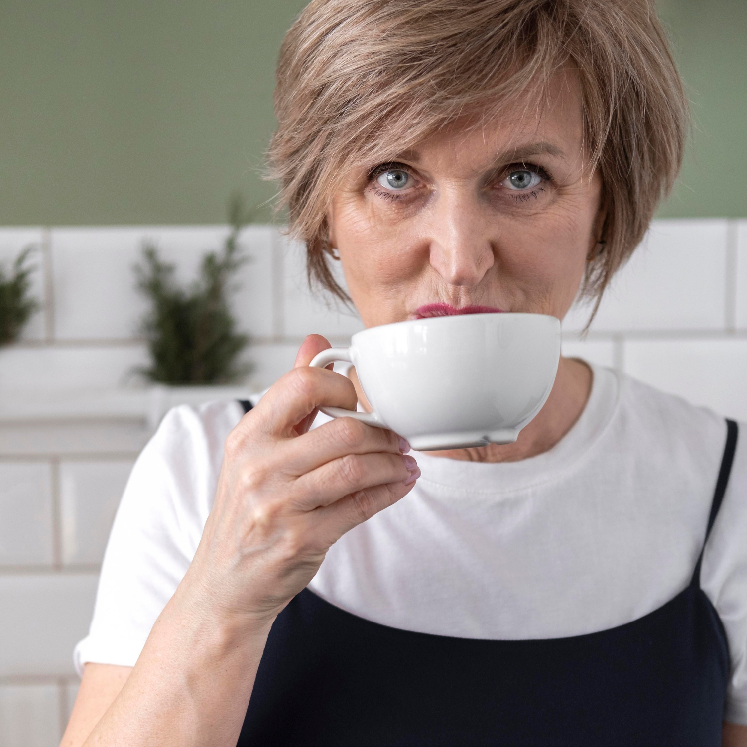 A smiling senior woman holding a ceramic cup | Source: Freepik