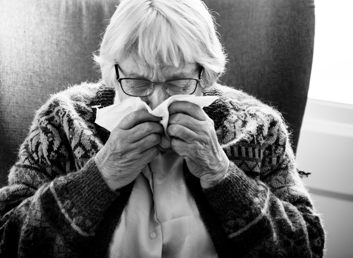 Grayscale shot of a senior woman using her handkerchief | Source: Freepik