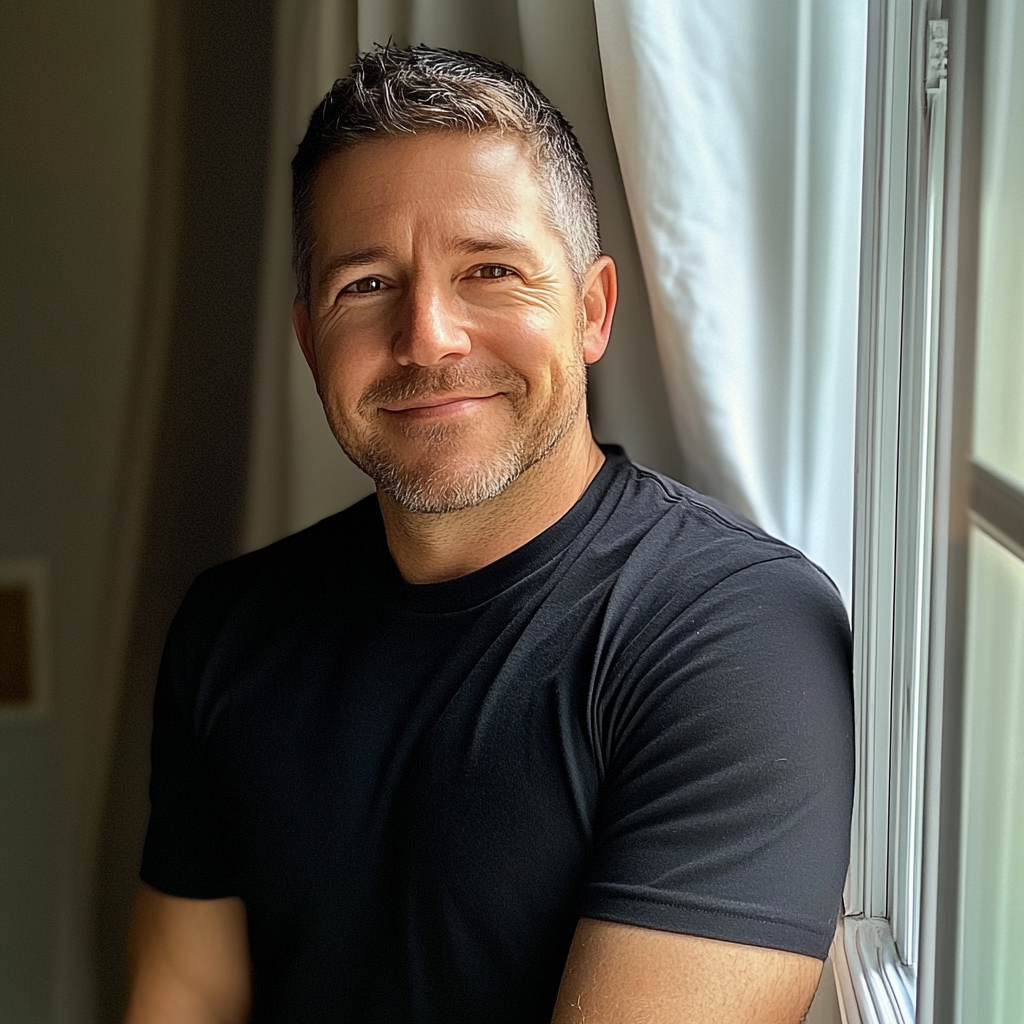 A smiling man standing by a window | Source: Midjourney