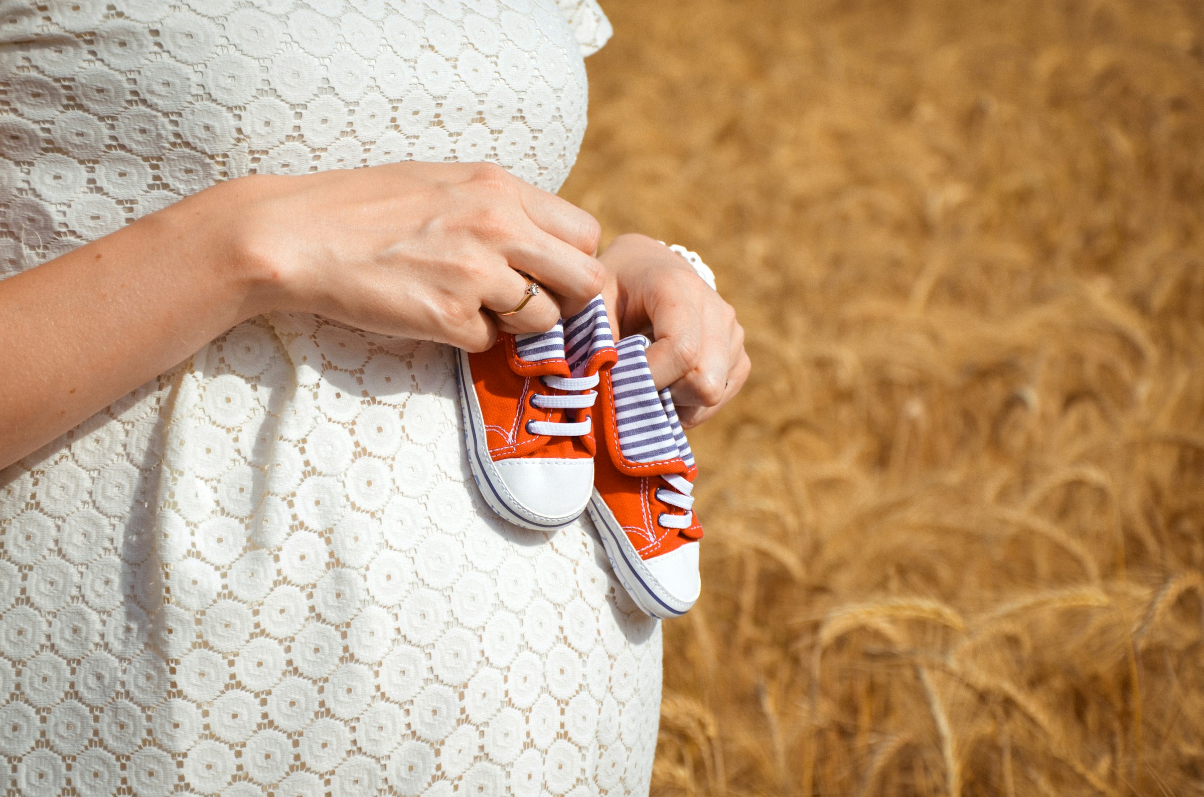 A pregnant woman holding tiny baby shoes | Source: Unsplash