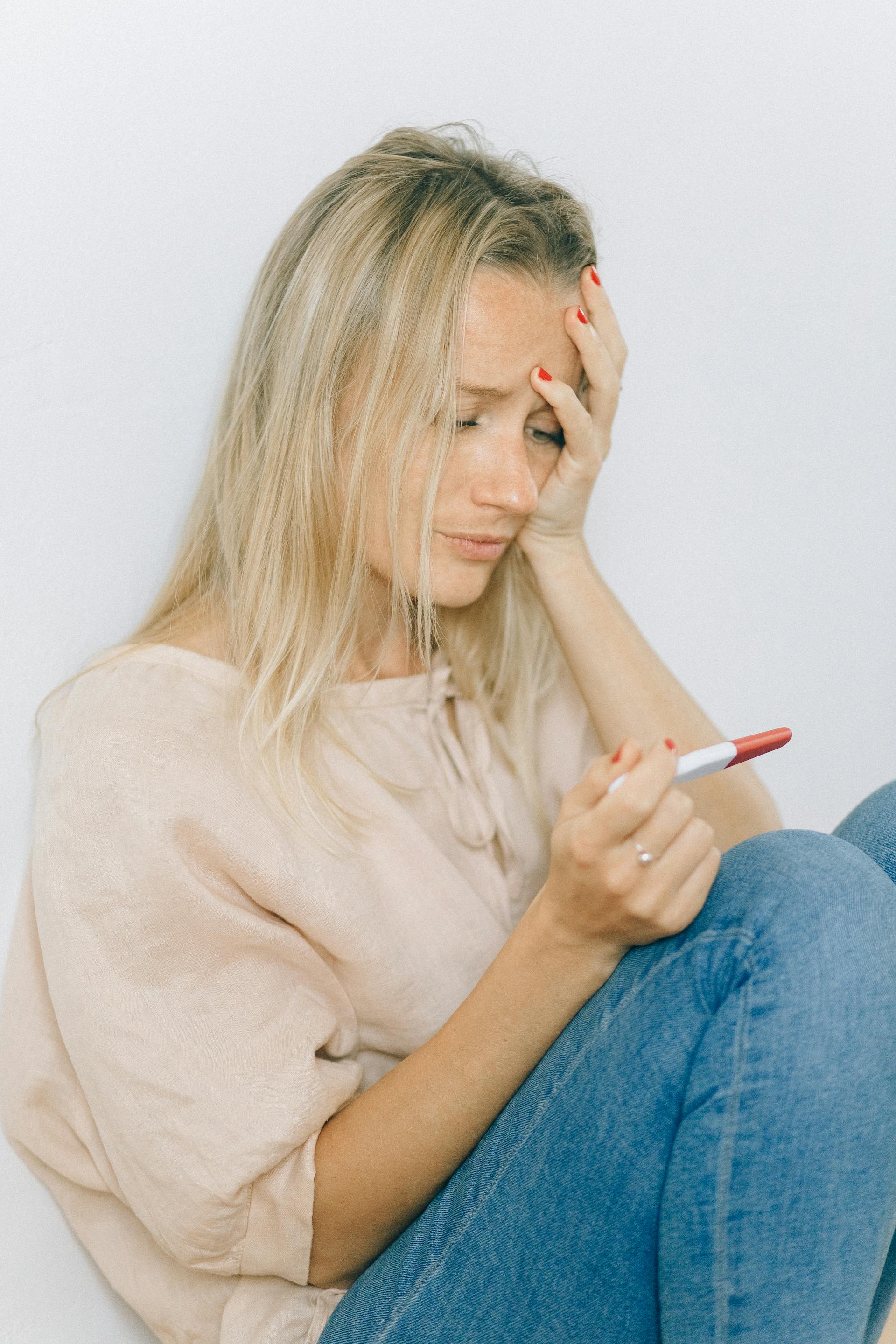 Depressed woman looking at a pregnancy test | Source: Pexels