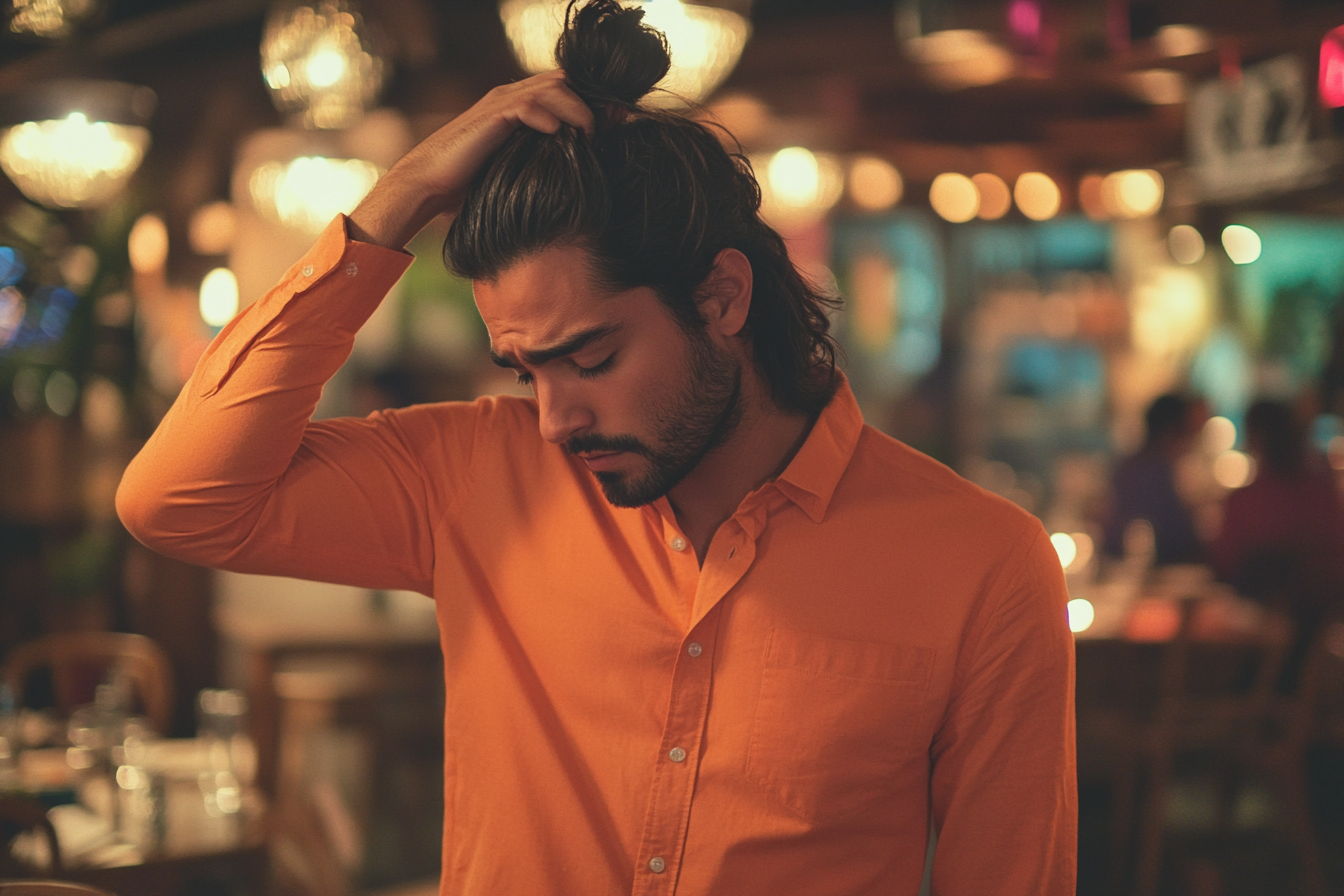 Un homme debout dans un restaurant, se touchant les cheveux, l'air triste et fatigué | Source : Midjourney