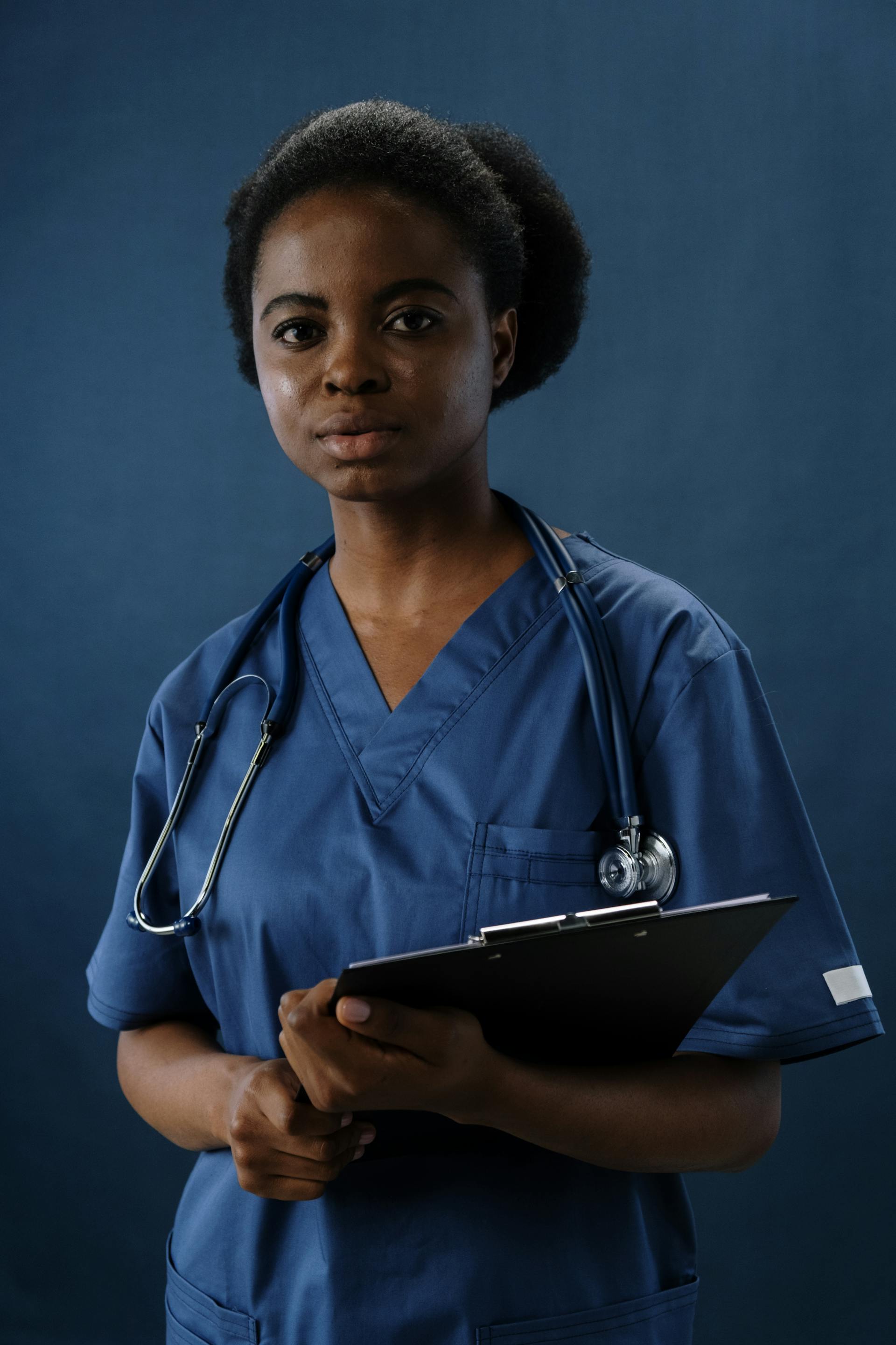 A hospital staff in scrubs holding a clipboard | Source: Pexels