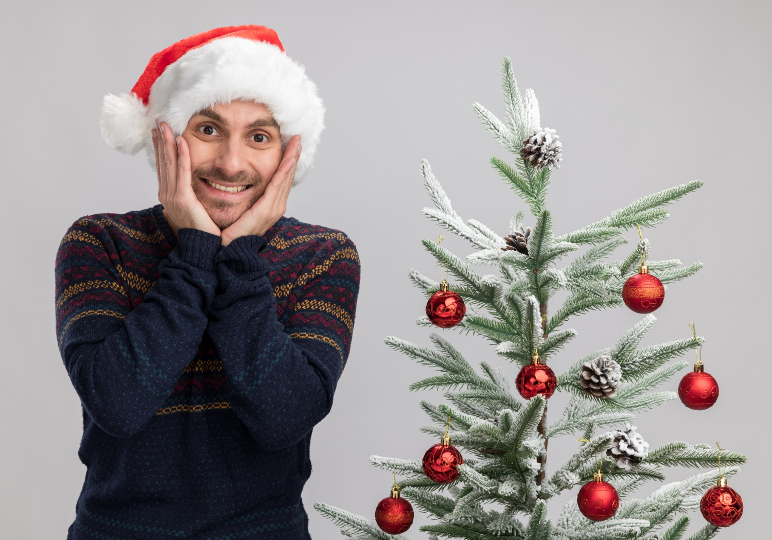 An excited man standing near a Christmas tree | Source: Freepik