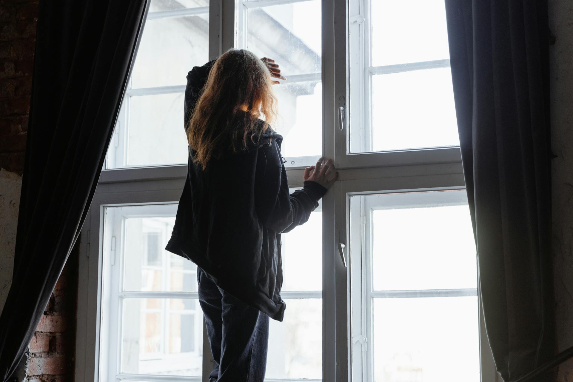 A woman standing near a window | Source: Pexels