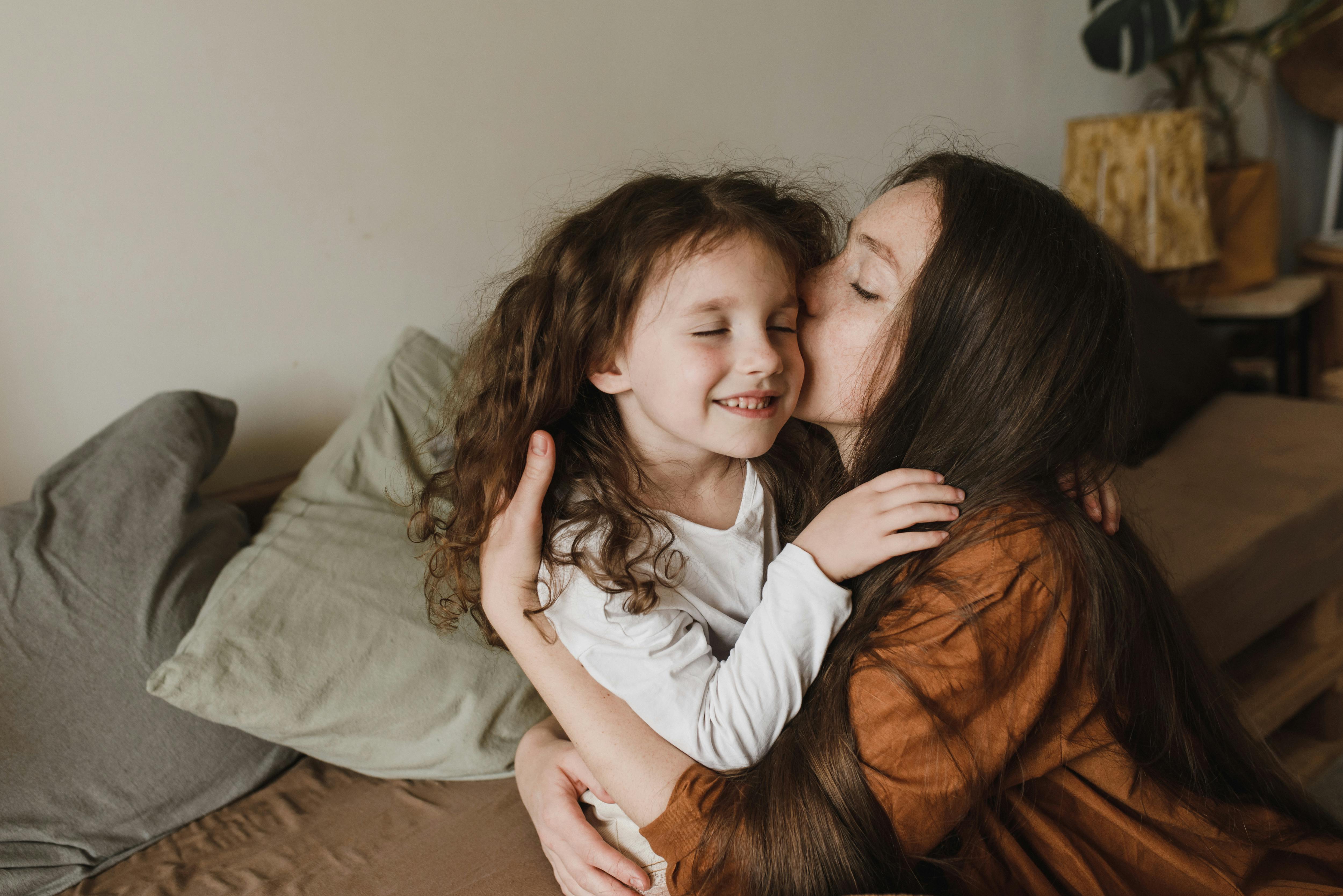 A mother snuggling her daughter | Source: Pexels