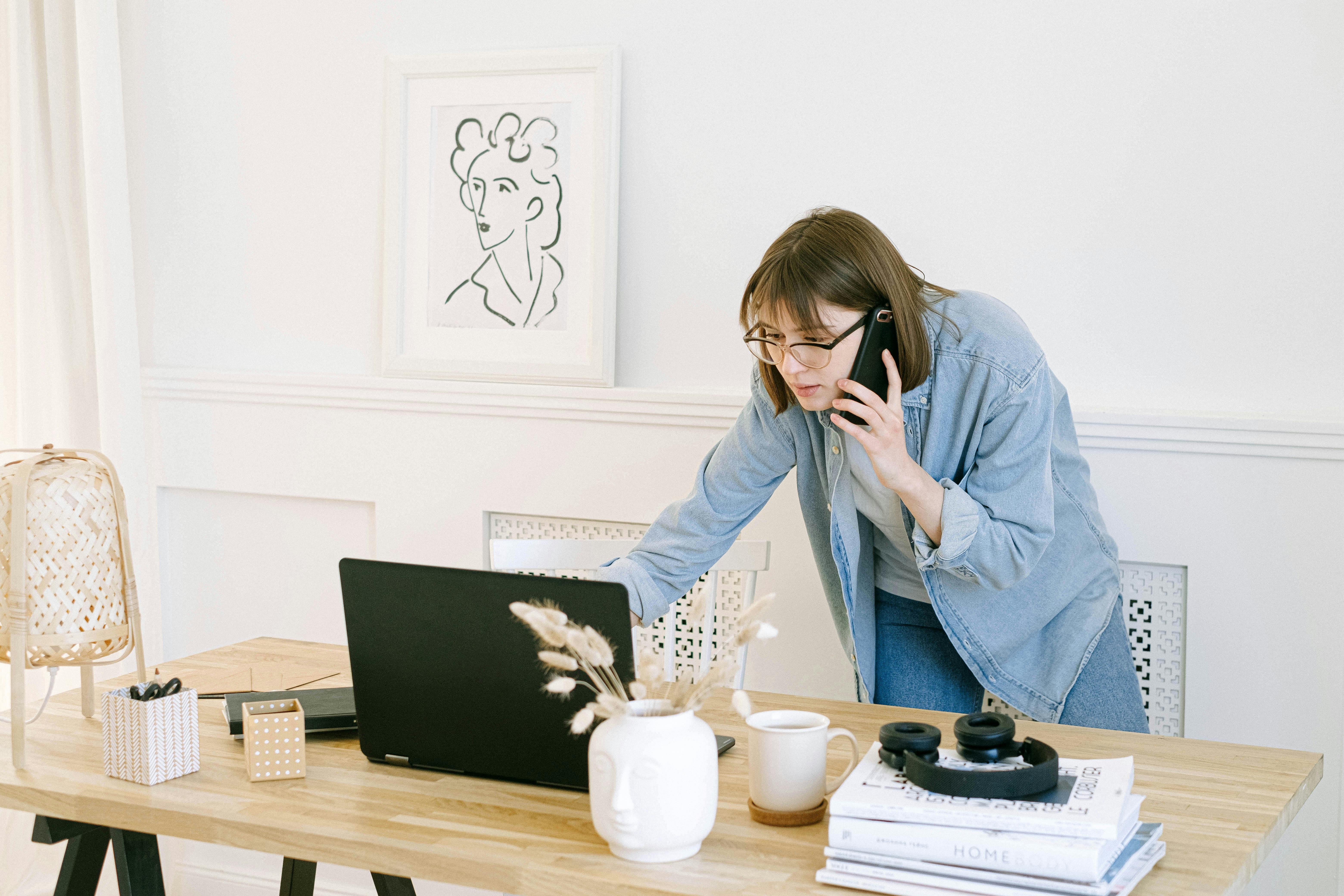 Woman talking on the phone while looking at a laptop | Source: Pexels