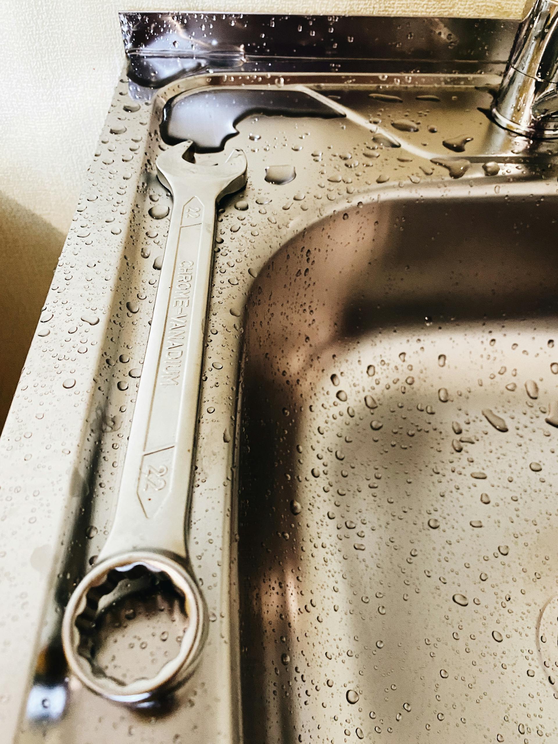 Wrench lying on a stainless steel sink | Source: Pexels