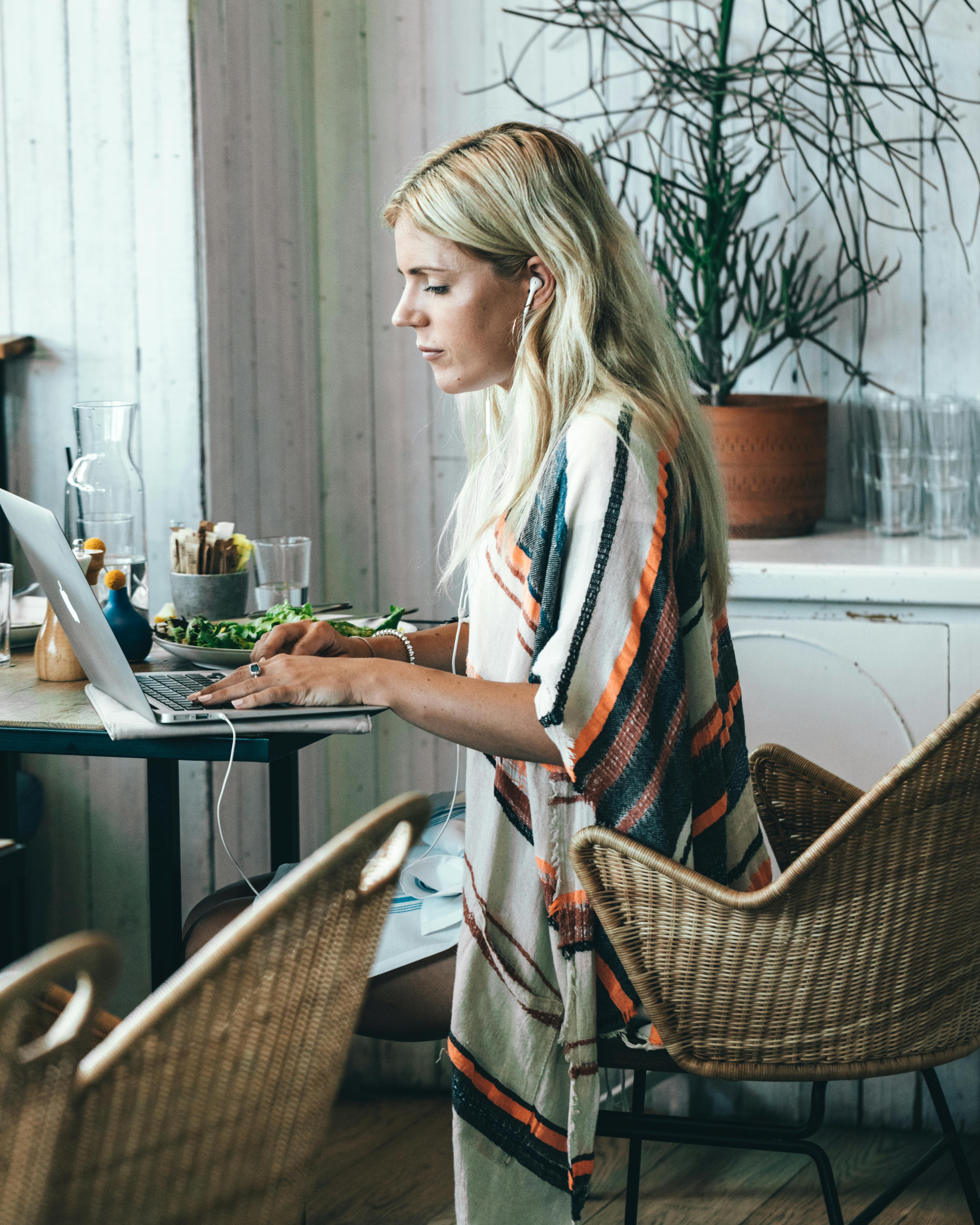 A woman wearing ear phones while using a laptop | Source: Pexels