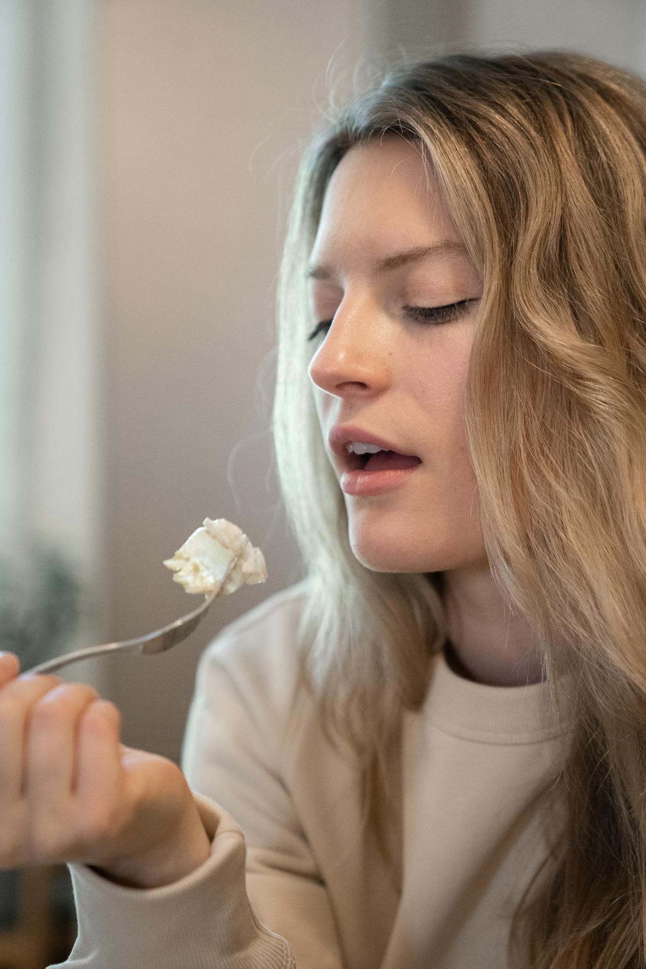 A woman eating food using a fork | Source: Pexels