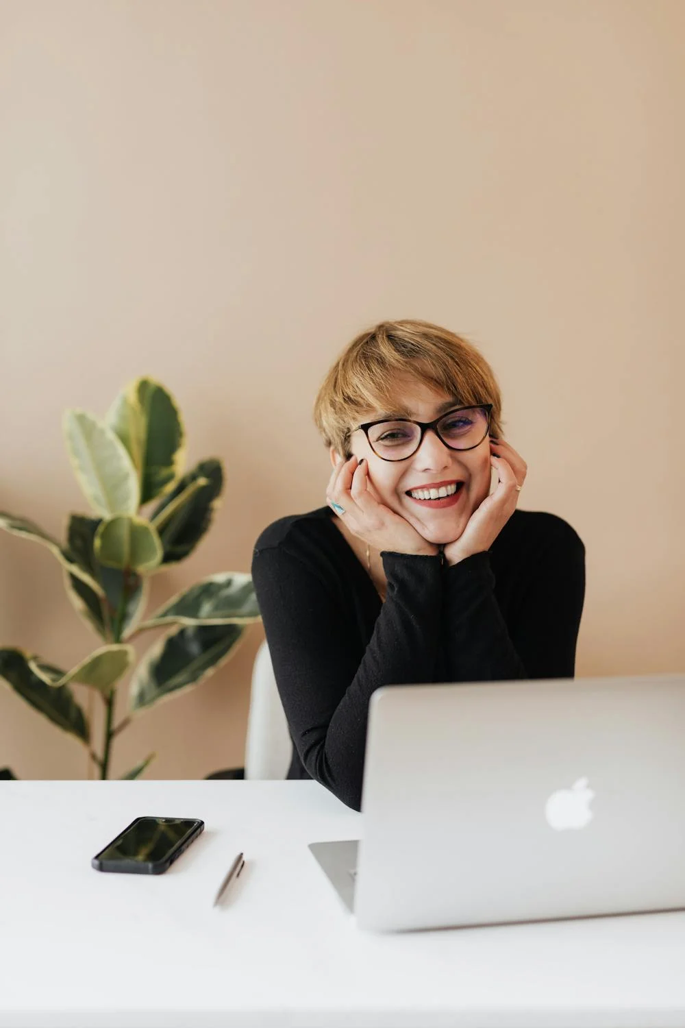 Una mujer sonriente en su oficina | Fuente: Pexels