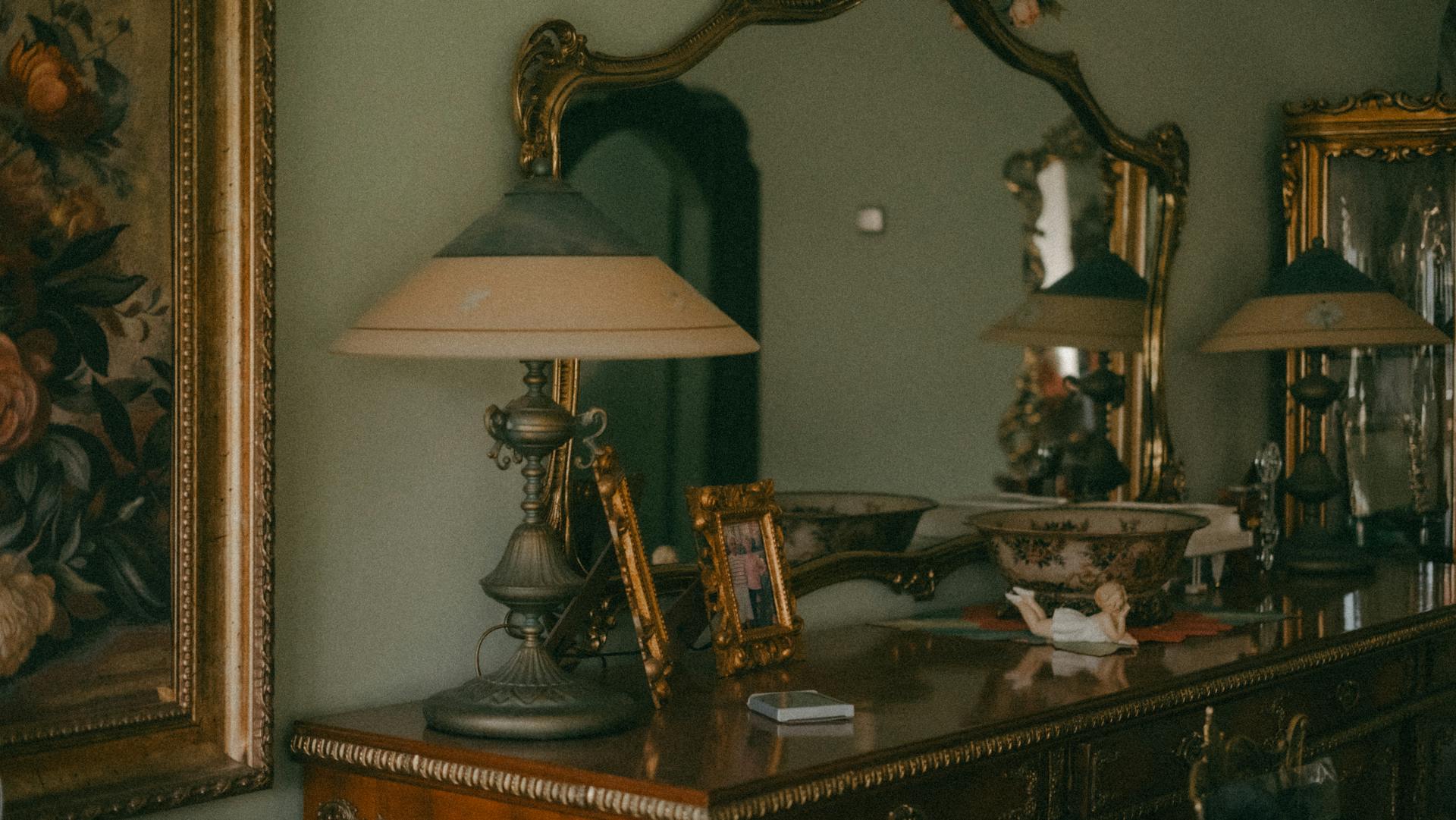 A wooden antique dresser with a lamp and gold frames on top | Source: Pexels