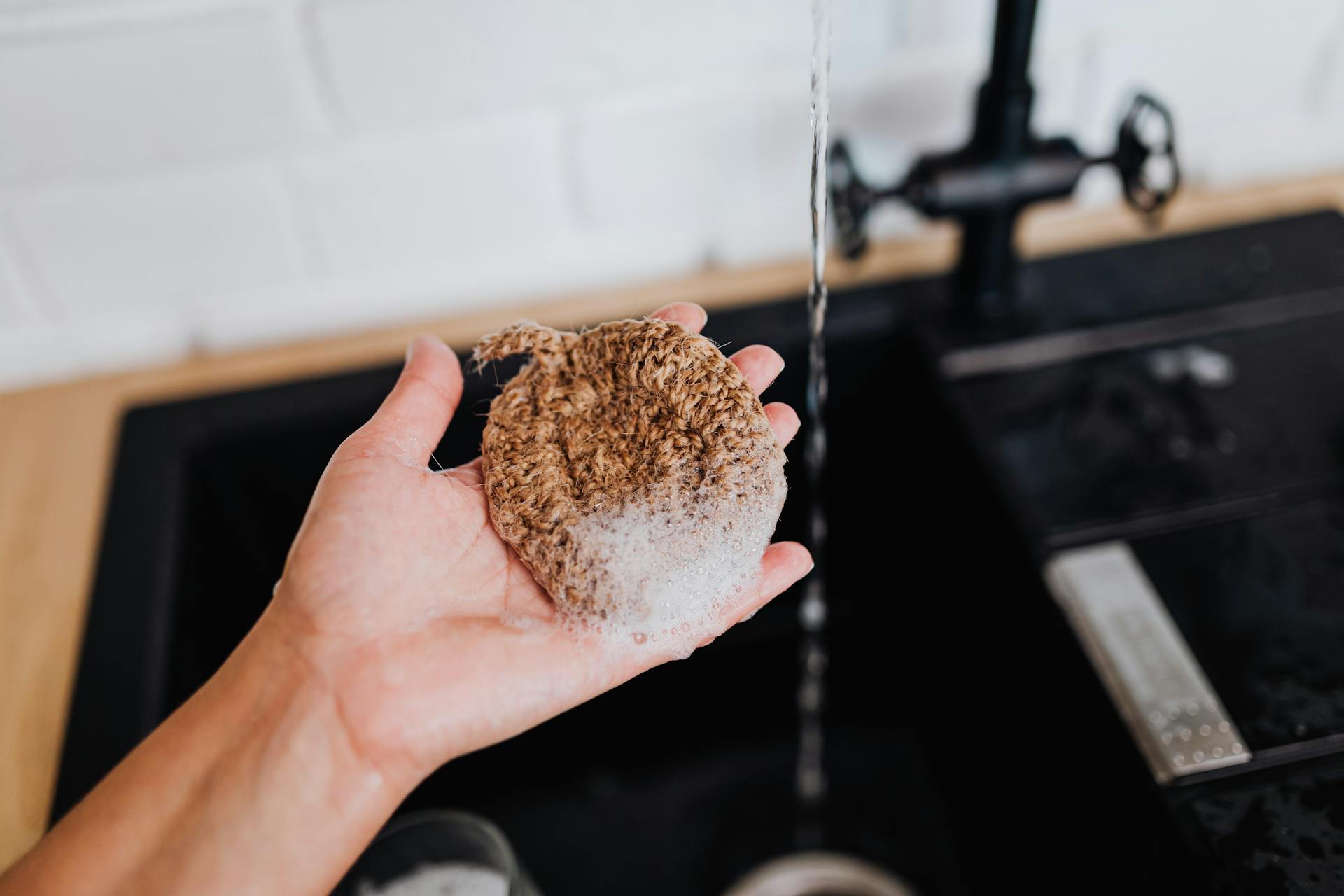 A woman holding a soapy scrubbing pad | Source: Pexels
