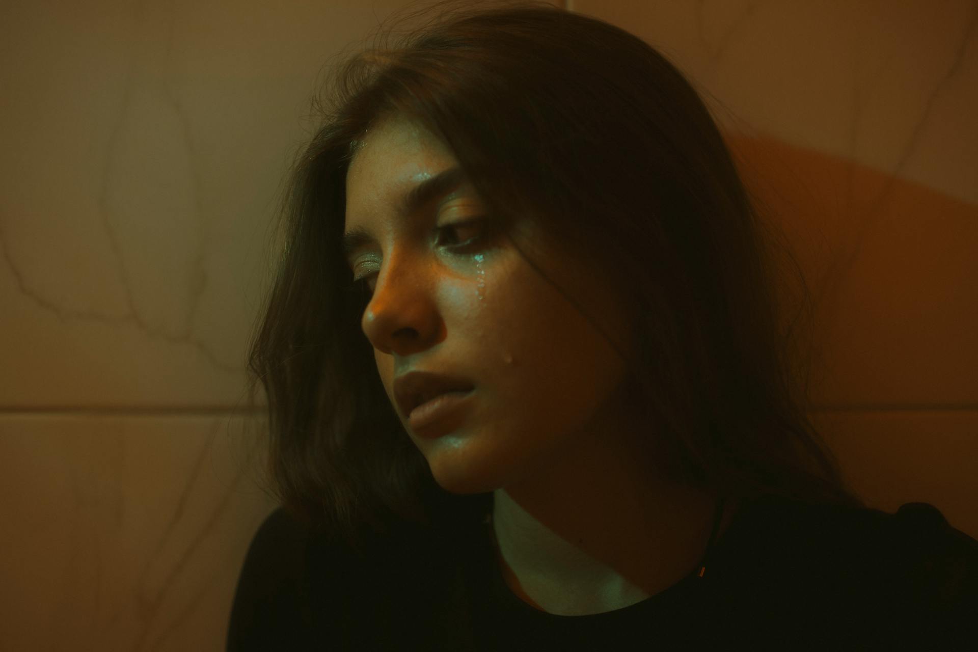 A young woman standing against a wall and crying | Source: Pexels