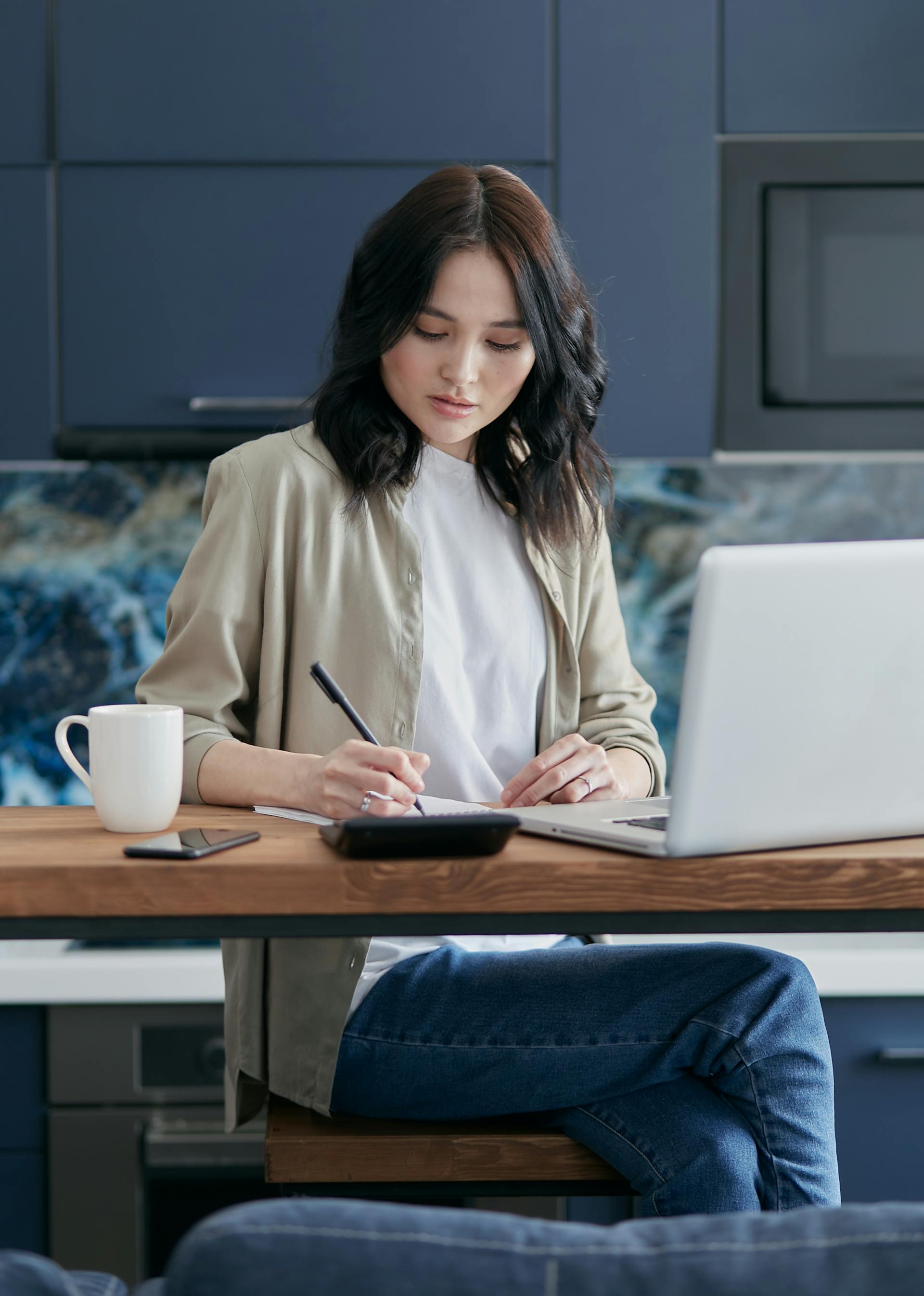 A woman making notes while using her laptop | Source: Pexels