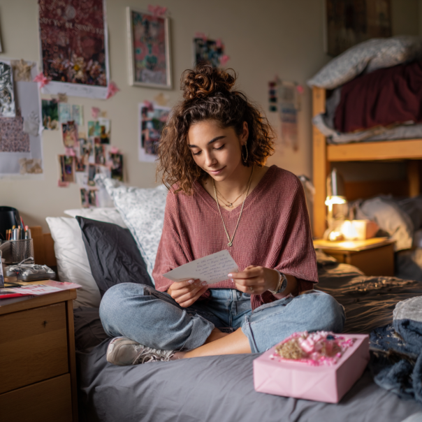 A girl reading a note on her bed | Source: Midjourney
