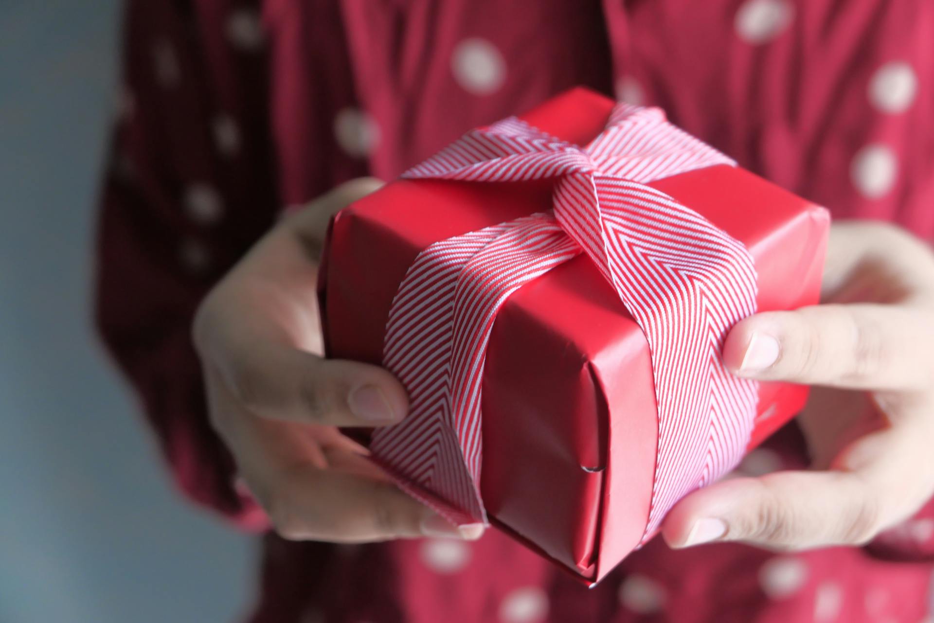 A woman holding out a small gift-wrapped box | Source: Pexels