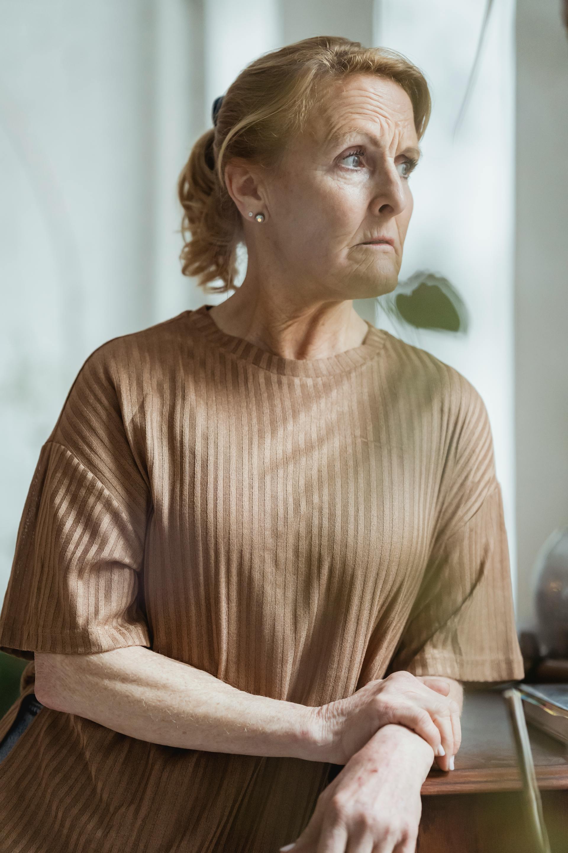 A mature woman in a brown sweater with a worried expression looking away from the front | Source: Pexels